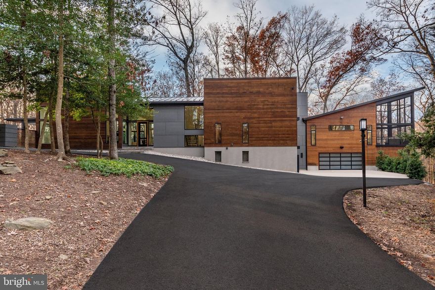 A custom built modern, yet perfectly practical, contemporary designed by renowned-Architect Mark Hughes of Georgetown’s Harrison Design, 10610 Vickers Drive offers the perfect escape to a tranquil 5-plus acre fully-wooded estate, backing to miles of parkland that will never be developed, yet only 5 miles from Tysons Corner, 11 miles to Washington DC, 7 miles to Dulles Airport and 15 miles to Reagan National via either 66 or the Dulles Access Road, both of which are only 3 miles from the driveway.

With recent zoning changes encouraging Accessory Living Units, the equestrian-zoned property allows infinite possibilities for expansion into a private compound with a stable, or preserve the property and its oak, ash, poplar, and Virginia holly-laden pristine forest as private respite from world.  The property is directly connected to hundreds of miles of equestrian and the Fairfax Country X-country trail system – yet only minutes from Tysons and DC.

Every detail of this remarkable home has been considered, from the 5”plank, hand-finished oak heartwood floors, to the custom inset kitchen cabinets, highlighted with rift-sawn oak accents, quartz countertops, and Miele appliances, including a combi-steam oven and two dishwashers, as well as drawer fridge and ice maker. The kitchen opens to the rear to a large Ipe deck overlooking miles of parkland, as well as the enormous south-facing sun-filled living area with 14 foot ceilings and a double-sided gas fireplace.  A 12 foot high portrait window frames the heated infinity-edge pool and year-round spa with a therapeutic jet-packed captain’s chair.  Adjacent to the pool is yet another Ipe deck, this one covered and heated with an enormous dining area that includes a 4 foot built in Lynx gas grill and side burner.

It is the 2000+ square foot Owner’s Suite that sets this home apart for all the others.  With a wall of glass facing the top of the tree canopy of the surrounding forest, the Owner’s Suite is highlighted with a heated screened porch with soaring 20 foot ceiling with Ipe flooring and a double-sided gas stone fireplace separating the sleeping chamber from the sitting area.  Moving into the spa-like bath, there are two walk-in closets fully fitted with custom cabinets and shelving, the larger of which with a full size washer and dryer, serving as a second laundry for the Owner’s personal use.  The spa-bath features 10 foot ceilings with wall-to-ceiling custom windows with built in blinds, providing the same expansive forest views from the nearly 50 square foot glass steam shower outfitted with a rain head and body sprays.  Adjacent to the steam shower is a full-sized cedar-lined stone-heated sauna.

Beneath the Owner’s Suite sits over 2000 square feet of flexible, fully-conditioned space, featuring a bathroom, wet bar, 16 foot projector TV, and finished with polished concrete flooring.  In addition to the fully-outfitted gym with large windows facing the forest with a professional gym floor, this space can be used as a ballroom, a showroom for a car collection (think Ferris Bueller) or partitioned into additional bedroom space.

Other features of this very special home include a whole-house natural-gas powered generator (it even powers the pool in the event of an outage), a French-oak paneled powder room (with a Koehler Numi bidet), a three-story rift-sawn oak paneled elevator, a master-cabinet-builder produced custom Murphy bed, custom closets throughout, and whole-house Sonos audio system.