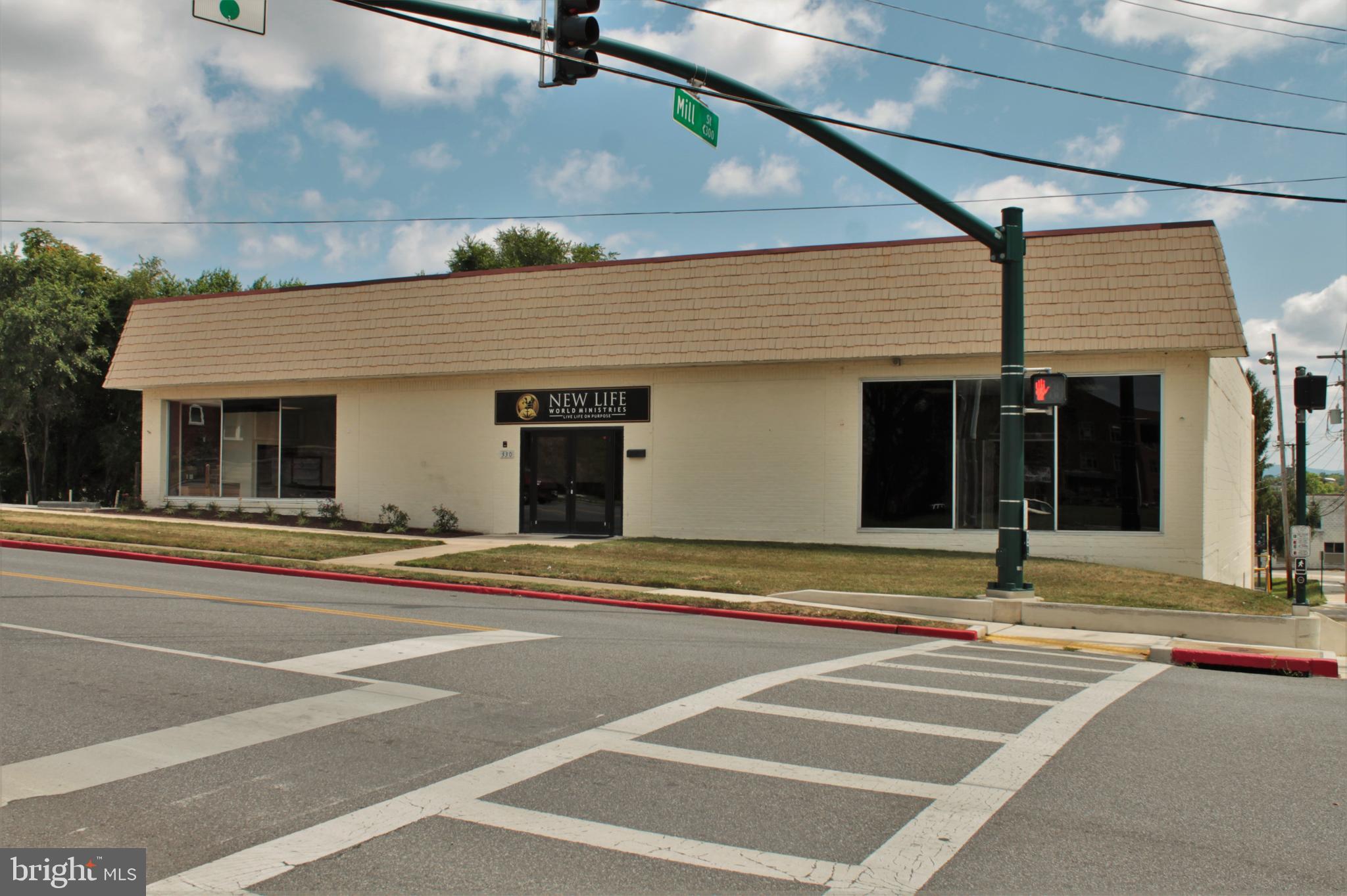 This property offers a combined total of 12,480 finished square feet. The main floor can be accessed from Frederick Street while the lower level can be accessed at grade from Mill Street and a rear alley. The property is located on a corner lot and offers over 45 paved parking spaces. Directly across the street is Hager Park and directly behind the property is a softball field and complex. There are numerous medical offices and other commercial and residential uses in the area. The zoning is commercial general.
The main level of the building was most recently operated as a church. Prior to that it was an open retail space. Currently the main level offers a large reception area, 3 ADA compliant bathrooms, 4 large meeting rooms, 3 private offices and various other storage rooms and private rooms. The main level also offers a large auditorium measuring 40 x 64 and includes a sound booth, stage and built-in retractable movie screen. The main level includes 3 zones of heating and cooling and is on a separate electric meter. You'll find a kitchenette located in the front lobby area of the building.
The lower level offers at grade entry and includes ADA compliant ramping once inside the building to access the lower level. This level offers 15+ foot tall ceilings, 2 additional bathrooms, storage room and a large open warehouse space, event space or meeting space. This level is heated by hanging natural gas forced air furnaces but offers no central air. The lower level is on it's own electric.
This property would work great for a childcare facility with parks directly next door. It could also be used as a church, office space, warehouse space, school, retail, event center, or other use.
In addition to the building being listed for sale, the owners would consider renting the top floor and lower level separately or combined. See MLS# MDWA2001506 for leasing details.