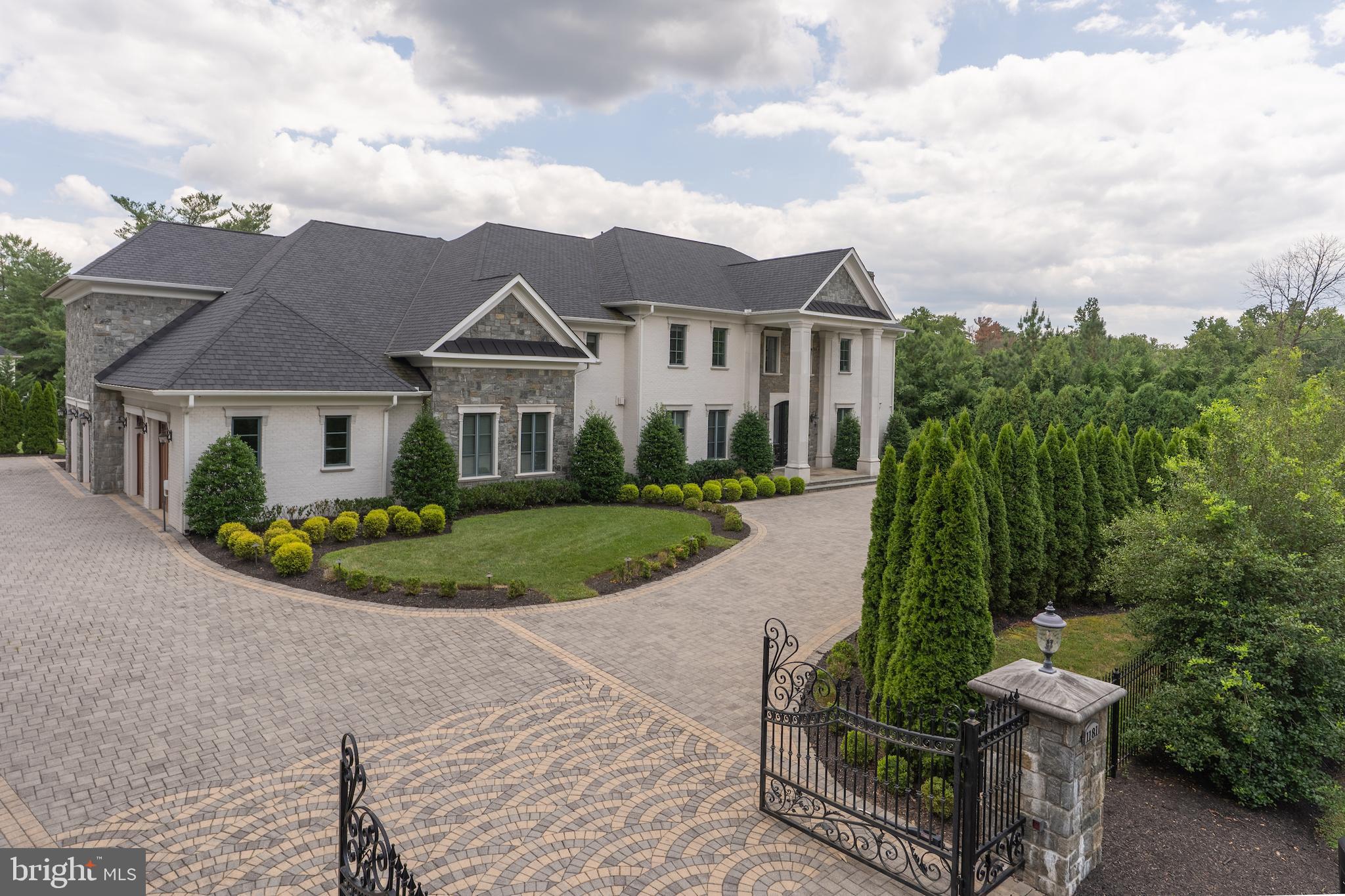 Introducing Eleven-Eighty-One Ballantrae Lane—a one-of-a-kind estate completed in 2018, set behind private wrought-iron gates in the heart of prestigious Langley Farms, one of McLean’s most storied and exclusive enclaves. Developed and inspired by the great manor homes of Europe, this architectural masterpiece redefines luxury living just minutes from the Nation’s Capital.
Set on one of the final open lots in historic Ballantrae, the estate rises three spectacular levels, each richly appointed with bespoke finishes, imported materials, and exquisite design. From the moment you step inside the grand foyer—beneath a soaring 25-foot domed ceiling—you’re immersed in a world of refinement. Floor-to-ceiling windows frame the Versailles-style pool and manicured garden plazas, inviting natural light to pour into the expansive interiors.
Every inch of this residence is a showcase of artisan craftsmanship. The chef’s show kitchen, featuring Italian cabinetry by Bordignon Camillo, is paired with a fully outfitted caterer’s kitchen with UNICA cabinets—creating the ideal setting for intimate family meals and large-scale entertaining. Flanked by a formal cordial salon, the embassy-sized dining room sets the stage for elegant hosting. Rich 5” white oak floors flow throughout the home, complemented by custom Murano chandeliers, intricate trim work, lighted tray ceilings, and artistically forged scrolled iron accents.
The main level also features a private esquire’s library, multiple entertaining salons, and a seamless flow to outdoor living spaces. An elevator services all levels, adding ease and accessibility throughout.
Upstairs, world-class bedroom suites provide luxurious comfort and privacy with spa-style baths and generous wardrobe space. The primary suite is a sanctuary with dual dressing rooms, a lavish bath, a sitting area, and direct terrace access.
The lower level is an entertainer’s paradise. A circular party room, club lounge, central bar, state-of-the-art cinema, gym, sauna, and a professionally designed wine cellar await—all grounded by Versace-imported ceramic flooring from Italy. Whether hosting a gala or relaxing in the spa, the club level seamlessly blends indulgence and utility.
Situated at the corner of Ballantrae Lane and Dolley Madison Boulevard, this home occupies a rare and prominent position in one of Virginia’s most distinguished neighborhoods—home to ambassadors, dignitaries, and captains of industry. With its meticulous craftsmanship, timeless European inspiration, and state-of-the-art amenities, 1181 Ballantrae Lane is a legacy estate.
This is your opportunity to own a modern manor of rare distinction and become part of Washingtonian history.