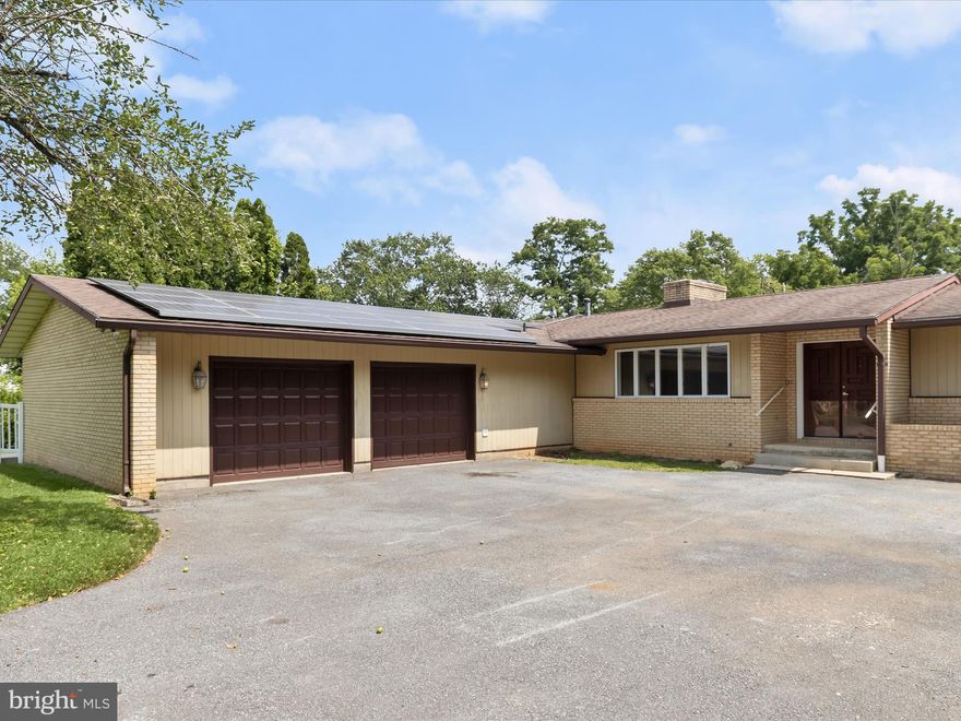 Step into this stunning home through stately double doors onto a welcoming slate floor. The interior features gleaming hardwood floors complemented by neutral paint throughout. The expansive living room boasts a wood-burning fireplace surrounded by ceramic tile and sliders that lead out to the backyard. The heart of the home is an enormous eat-in kitchen featuring a large two-level island with a breakfast bar, granite countertops, and custom soft-close cabinetry. It offers an abundance of storage space, electric cooktop, double sinks, and stainless-steel appliances including double ovens and a convenient pot filler. A built-in banquet with storage and pendant lighting adds charm, while large arched and sunny windows showcase views of the backyard. A spacious laundry room/mudroom with built-in cabinets and a garage equipped with an extensive woodworking workshop provide practical spaces for everyday needs. A conveniently located powder room on the main level adds to the functionality. The primary bedroom is a retreat with gleaming hardwood floors, oversize sliders leading to a covered patio, and double closets. The gorgeous master bath features double sinks, granite countertops, custom cabinetry, and a modern walk-in shower with seating. There are two additional generously sized bedrooms, each with sliders leading out to the yard, and a second full bath. The enormous lower level offers built-in storage and limitless potential for various uses. Outside, the very large rear yard is fully fenced and backs to trees, providing privacy and a serene backdrop. Ample parking is available with a double attached garage providing space for at least six cars. This home combines luxurious amenities with practical features, offering an ideal blend of comfort, style, and functionality for modern living.
