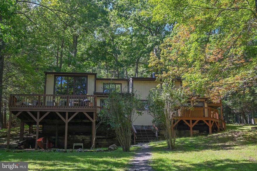 Deep Creek Lake lakefront, nestled beneath a canopy of trees,  this 4 bedroom/4 bath home has wonderful relaxing lake and mountain views.  Home boast a hardwood floor great room with massive native stone fireplace.  Cozy den, sauna, lakefront deck, lakefront hot tub, covered entry porch, large rooms throughout. Enjoy the best of Deep Creek lake life outside on the expansive deck, on the dock watching the evening stars or curled up in front of the fireplace on those cooler days.