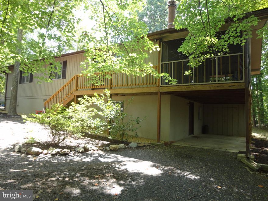 Nestled in the Trees in Beautiful Lake of the Woods is this charming five bedroom three bath home with open living area, corner fireplace, gleaming hardwood flooring, and fully screened porch!! Walkout lower level to carport with storage area and backyard with horseshoe pit.  Enjoy the lake, beaches, pools, tennis, golf, walking trails and all the amenities offered in this established community!