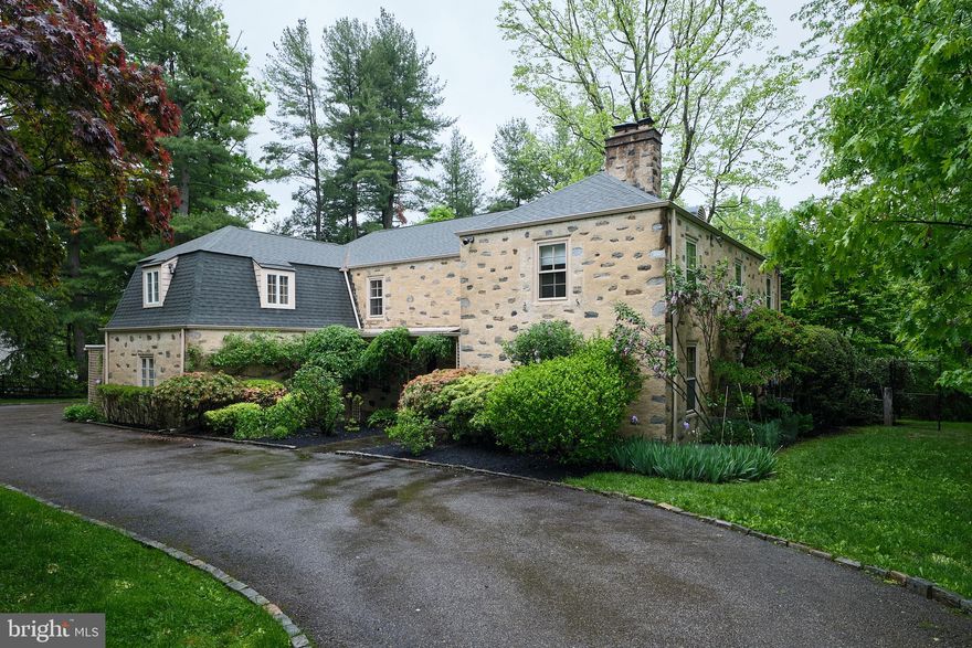 Step into this exquisite 5-bedroom masonry stone colonial in sought-after North-side Bryn Mawr.  Crafted in 1950, this McDevitt home blends tradition with innovation.  McDevitt's mastery of light is evident throughout, with expansive deep-set windows and walls of glass with doors gracing the public spaces. Situated in a serene enclave with no through traffic, this neighborhood offers a safe and walkable haven for residents and children.
As you enter through the covered patio, the hall foyer welcomes you with hardwood pegged floors that extend throughout the first floor.  To the right of the front door is the powder room next to a cozy den with a fireplace surrounded by built-in bookcases.  Down the hall, French doors open to a beautiful, light-filled, formal living room with a fireplace surrounded by built-in bookcases and boasting a wall of metal composite paned windows with two doors to the back flagstone patio.  A rounded archway leads to the elegant formal dining room, adorned with metal composite-encased windows and two more doors to a flagstone patio and backyard.  These stunning windows in the living room and dining rooms provide abundant natural light and spectacular views of the private grounds and mature plantings.  The kitchen features a gas stove, ample counter space, a walk-in pantry, an egress door to the attached two-car garage, back stairs to the second floor, and access to the basement.  Adjoining the kitchen is an expansive family room with cathedral ceilings, built-ins, a screened-in porch at the end of the room, and more access to the outdoor flagstone patio through large window sliders.
Upstairs, the main bedroom suite impresses with a private full bathroom, two walk-in closets, and a second full bathroom with a tub connecting to an adjacent 2nd bedroom, nursery, office, or owner's retreat room.  Two additional bedrooms share a Jack-and-Jill bathroom, while the fifth has a separate ensuite.
The lower level offers abundant open space, mechanicals with a workbench, and quality storage closets.  Outside, the property delights with flat ground for play, mature perimeter hedgerows and trees for privacy, a generous, enclosed flagstone patio with gardens, a greenhouse, and a shed.  Located on Colebrook Lane, this enchanting home is within easy reach of SEPTA (R5), Suburban Square, top public and private schools, Bryn Mawr Film Institute, Ludington Library, terrific restaurants, and fabulous shopping.  It is truly a must-see!

NO SHOWINGS BEFORE FRIDAY, 5/10, AT 11:00 AM
ALL SHOWINGS BY APPOINMENT ONLY
FRIDAY, 5/10,  BROKER’s OPEN FROM 12:00-1:00 PM