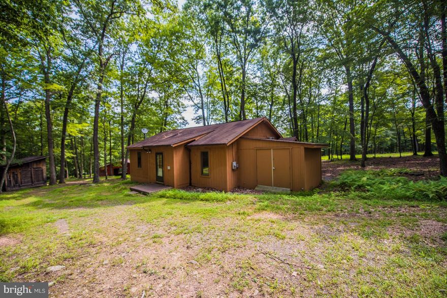 1184 sq ft cabin privately situated on 10.86 Acres West of Berkeley Springs. One level living with  2 BR, 1.5 baths. Tongue & Groove Ceilings, laminate flooring, kitchen, dining, and family room have open floor plan w/ meanering stream. 12 x 16 screened deck with ceiling fan for enjoying quiet, relaxing lazy days. Attached 12 x 12 workshop + 3 stall 36 X 36 barn for horses + 12 x 20 storage shed.