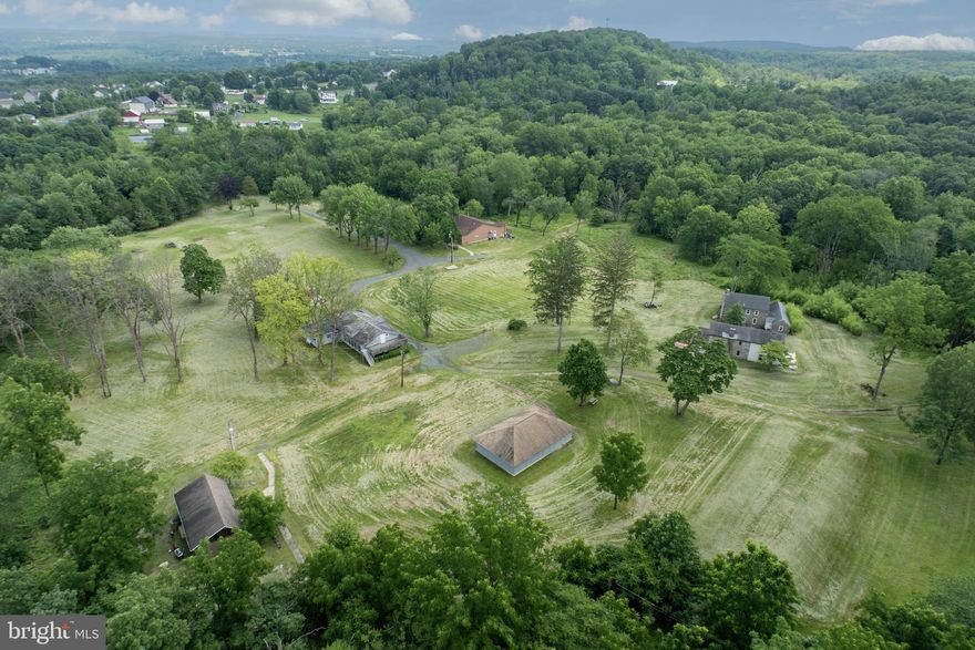 Incredible Opportunity on 120+ Acres in Montgomery County – Historic Retreat with Endless Potential and many uses
Nestled in a peaceful and secluded setting, this remarkable 120+ acre property offers a rare opportunity to own a piece of Montgomery County history. Currently used as a retreat, the estate features two charming stone historic homes in need of rehab, a spacious dining hall equipped with a full commercial kitchen, a bunkhouse can house 22 people with office spaces, ADA-compliant bathrooms, multiple utility/storage buildings, one utility building was formerly a pavilion used for outdoor cookouts, meetings, and community gatherings-and could easily be converted back from a utility shed to a pavilion, further adding flexibility for events and recreation. A ropes course adds to the property's versatility, making it ideal for retreats, conferences, therapeutic programs, or educational gatherings.
A unique feature is the 8.1-acre section (see plot plans) known as “Woodrock” which has a separate road access from Schaeffer Rd and is excluded from the conservation easement-opening the door for potential subdivision or future development. Woodrock does have multiple buildings on it in very poor condition and a basketball court. Please do not enter buildings. 
Zoned R-2, the property supports a wide variety of uses "by right," including residential, general farming, forestry, nurseries, detached dwellings, accessory professional office or personal services, accessory Instructional services and municipal uses. Additional uses are permitted by conditional use or special exception, offering tremendous flexibility. Potential options range from private schools, places of worship, riding academies, veterinary office, and kennels to camps, family day care, event spaces, recreational facilities, and therapeutic communities.
The site has a long-standing history of service to the community, formerly known as Fellowship Farm and now operating as Working Together. It has hosted summer camps, conferences, transitional housing, and wellness-focused programming.
The landscape is truly breathtaking with rolling hills, open meadows, a small pond, and wooded areas, all accessible via a long private drive. Incredible views from the top of the “outlook”  up the trail… make for some relaxing sunset cocktails overlooking the horizon/ valley. Fire pits and rustic rock circles, perfect for group gatherings, evening storytelling, or quiet moments of reflection under the stars. The property includes a conservation easement and a gas line easement. Please investigate how these may impact your use. Just minutes to Route 422 and Route 100 and under 40 miles from Philadelphia, this unique property is ideally located for a wide range of future uses.
This is a one-of-a-kind opportunity to own a vast, multi-functional property steeped in history and surrounded by nature, perfect for visionary nonprofits, institutions, or those seeking a secluded and flexible estate.
See listing agent for disclosures, easement documents, and township information before calling the Township; this may answer many questions and is a preferred method for the zoning officer. There are 2 parcels included in this sale, see agent remarks.