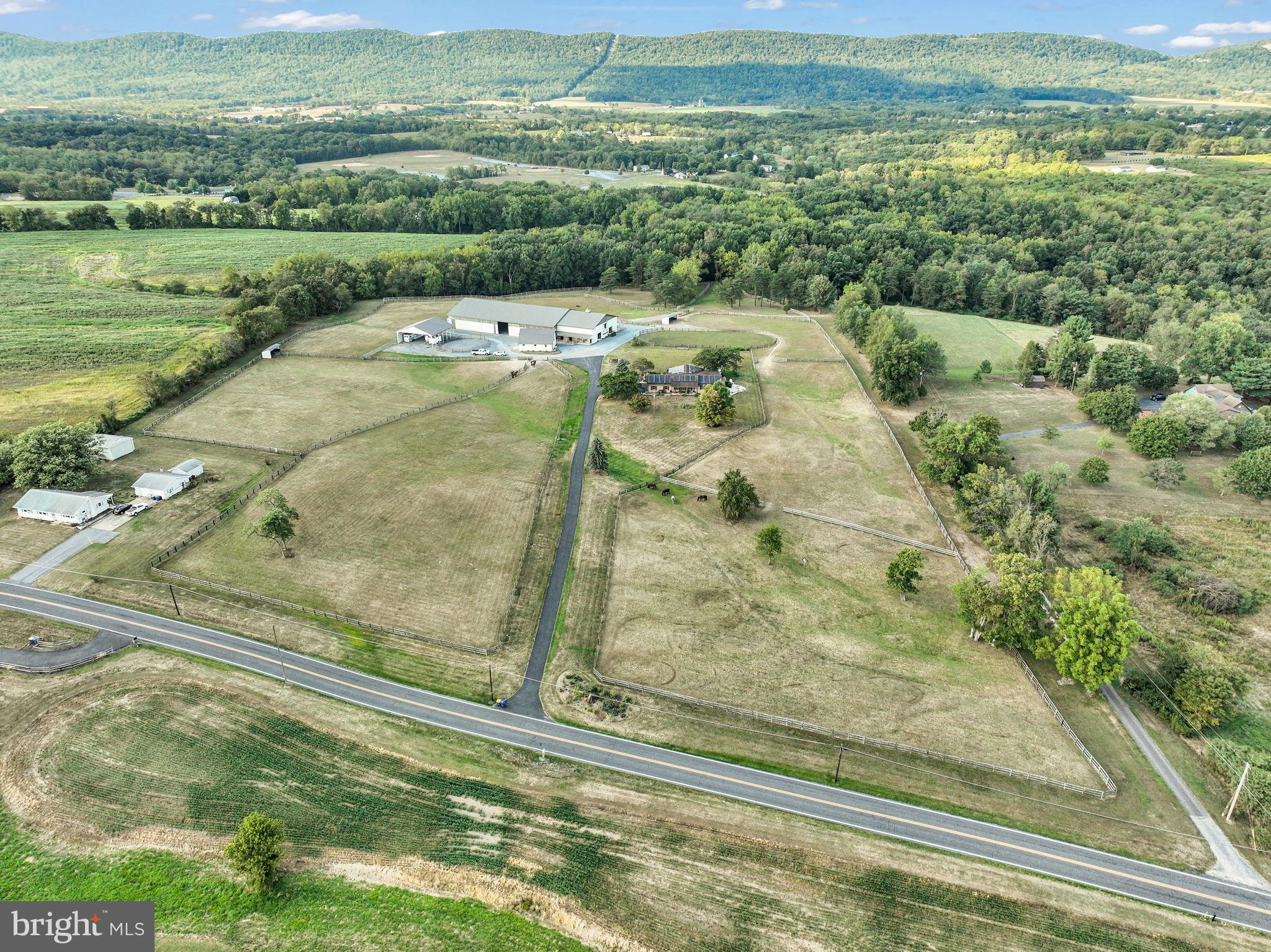 Welcome to Dreams Come True Farm, a breathtaking 24-acre equestrian paradise nestled in the heart of coveted Middlesex Twp, within the esteemed Cumberland Valley Schools. This turn-key farm, alive with the spirit of possibility, currently boards 7 horses yet brims with untapped potential for greater rental income. Picture yourself surrounded by 10 lush, fenced pastures, two charming barns, and a sprawling 152x80 ft indoor riding arena with rubber mulch—perfect for chasing equestrian dreams. The immaculate main barn (70x48 ft) boasts 11 indoor/outdoor stalls, a tack room, a fly spray system, and space for 2,500+ hay bales, and is seamlessly connected to the indoor riding arena. A second barn (37x32 ft) allows for plenty of storage/office, or awaits your vision for expansion for more horses. The exterior structures also offer a 48x48 ft carport and additional storage. In addition, this property features a 80mX40m level grass driven dressage arena.
Atop a scenic hill, the 2,400 sq ft home captivates with picturesque mountain views from both front and back of the house. Inside, find 3 bedrooms, 2 baths, a 2-car garage, and a partially finished lower level. The open-concept kitchen, with its tall custom cabinetry and gleaming stainless appliances, invites warm gatherings. A grand great room with expansive casement windows frames vibrant sunsets, perfect for cherished family moments. The primary suite is a serene retreat, featuring his-and-hers closets, a luxurious soaking tub, a spacious walk-in closet, and a dual-head shower. A whole-house generator with a large propane tank ensures peace of mind.
More than a property, Dreams Come True Farm is a lifestyle—a harmonious blend of equestrian passion and tranquil family living. Seize this rare opportunity to own a legacy estate that stirs the heart and soul!