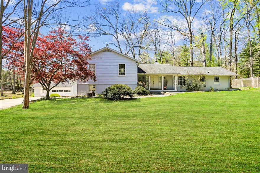 Discover 14400 Jones Lane, a beautifully designed modern split-level set on nearly 2.5 wooded and private acres in sought-after North Potomac - this is a home that truly must be experienced in person! Offering 3,566 square feet across three finished levels, this impressive home features five bedrooms and three full bathrooms. Defined by light-filled spaces, contemporary finishes, and a strong connection to the outdoors, the property combines comfortable living space with a striking natural setting. A gated drive, flagstone walkway, and double front doors welcome you into the residence, where hardwood floors, recessed lighting, high-end finishes, and an abundance of windows create a bright and inviting atmosphere. The back of the home is defined by walls of windows that flood the interior with natural light. The open main level living area centers around a gourmet kitchen with granite countertops, a large center island with breakfast bar, stainless steel appliances, a subway tile backsplash, and crisp white cabinetry. The kitchen flows into a breakfast area framed by a bay window and into a living room/sitting area with a dual-sided fireplace, large windows, and sliding glass doors opening to the deck. Adjacent to the kitchen, the formal dining room features wainscoting and a wall of windows with sliding glass door access to the deck. A private office with built-ins, a dual-sided fireplace, and another wall of windows with sliding glass door access provides additional flexibility and completes the main level. Outdoor living is a standout feature of the home. Spanning the length of the main level, the expansive deck creates an exceptional extension of the interior living space and includes a trellis and stone retaining wall that add character and definition. Multiple access points from the main level make it easy to enjoy the peaceful backyard setting, while the surrounding wooded acreage enhances the sense of privacy. Upstairs, the style and design continue for a cohesive look. The spacious primary suite offers an en-suite bath with a glass door shower and contemporary tile and finishes. Two additional bedrooms and a second full bath complete the upper level. Step down from the main level to the expansive lower level, which includes a fourth bedroom, full bath, dressing area, and a family room with a fireplace set within a stone accent mantel. Doors from both the family room and bedroom provide direct access to the patio and backyard, and a mudroom with outside access adds everyday convenience. A two-car detached garage provides exterior an extra storage room + a bonus lower level perfect for use as a wine cellar or cold storage.  This home offers a wonderful combination of space, design, comfort, and convenience, all within minutes of shopping, dining, entertainment, recreation, and major commuter routes. **Extensively pre-inspected with septic, well, water quality, radon, and full home inspection completed — providing buyers with confidence and transparency.**