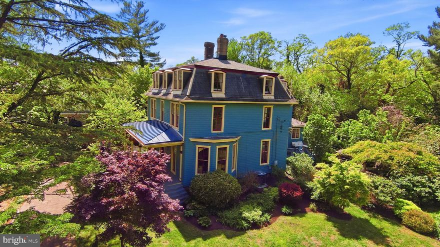 Known as the Wilbur House, or “Sunnyside,” this remarkable Second Empire Victorian offers a rare blend of historic character, architectural presence, and timeless charm. Built circa 1887 and sited on nearly a half acre, the residence is among the original estates positioned along the Ashton-Colesville Turnpike and retains many of its defining period details, including a mansard roof, original windows, interior paneling, hardwood floors, ceiling roses, moldings, and fireplaces.

A private drive leads through beautifully tended gardens with an in-ground irrigation system, arriving at a brick paved walkway and a welcoming porch—one of three porches found throughout the home. Inside, double entry doors open to an impressive foyer anchored by a striking staircase with hand-turned newel posts and spindles, paneled wainscoting, and original hardwood flooring. To the right, the light-filled double parlor features original floor-to-ceiling windows, an arched bay window overlooking the side yard, and two fireplaces. To the left, a large office with built-ins and a fireplace connect to a formal sitting room with wainscoting and a fourth fireplace.

At the rear of the home, the skylit eat-in kitchen combines modern finishes with historic texture, offering stainless steel appliances, quartz countertops, a full-height quartz backsplash, exposed brick, and French doors opening directly to the deck and private outdoor setting. A second rear staircase, butler’s pantry, mudroom with laundry, and half bath complete the main level. Upstairs, the second floor includes four bedrooms and two full baths, while the third floor provides a primary enclave with three additional bedrooms, a sitting area and adjoining primary ensuite bath.

The outdoor spaces are an escape from reality boasting a professionally designed garden that blooms year round, anchored by pergola wrapped in mature jasmine, wisteria, and clematis. Additional exterior features include a hot tub and an outdoor shower with a tankless water heater. While the home is tucked into a peaceful, serene setting it remains convenient to nearby attractions including; Sligo Creek Trail (0.2Mi), Zinnia Restaurant (0.2 Mi), The Fillmore & AFI Silver Theatre (0.8Mi), Downtown Silver Spring & Whole Foods 1Mi),  Sniders Super Foods (1.1Mi) and Silver Spring Metro/Downtown Silver Spring (1.3Mi) --offering both retreat-like privacy and everyday accessibility.

The home is listed as an individual site on the Montgomery County Master Plan for Historic Designation. For details regarding historic preservation tax credits, please consult applicable state and county resources. The seller prefers to convey the property "As-is", and pre-inspections are welcome.

Notable upgrades include: 
Main Floor outfitted with Central Heat/AC (2025),
Primary Ensuite bath (2025),
Quartz Countertops (2025),
Stainless steel appliance suite (2025),
Standing Seam Metal Roof Replaced (2024),
Refinished hardwoods in Dining, kitchen and adjoining parlor (2025),
All slate tiles repaired (2022),
Fully painted interior and exterior (2022/23),
New driveway with parking for eight cars (2013),
Rubber membrane roof (2012),
Restored function of front parlor fireplace with aluminum lining (2010)