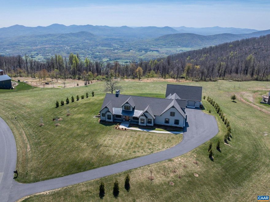 Located within the exclusive Elk Rock Meadow community atop Afton Mountain, this custom-built residence offers 5.77 private acres with unobstructed, year-round, million-dollar Blue Ridge views and direct adjacency to the Blue Ridge Parkway and Skyline Drive. The open floor plan with neutral paint and hardwood floors centers on a great room with wood-burning fireplace and full wall of sliding glass doors framing the mountain panorama. The gourmet kitchen features quartz counters, white cabinets, a professional-grade Viking cooktop, Zephyr exhaust system, and butler's pantry. Two primary suites each offer a private ensuite bath; two additional bedrooms and a full bath accommodate family and guests comfortably. Zoned climate control is provided by three separate HVAC units, and a whole-house generator ensures year-round reliability. Covered breezeway connects the main residence to a detached 30' x 50' shop with a half bath, commercial-grade lighting, partially finished upper level, and dedicated HVAC - an ideal space for the collector or hobbyist. A greenhouse and dedicated gardening room complete the outbuildings. Twenty miles west of Charlottesville and 12 miles north of Wintergreen Resort, this luxurious home is a dream come true!,Quartz Counter,White Cabinets,Fireplace in Great Room