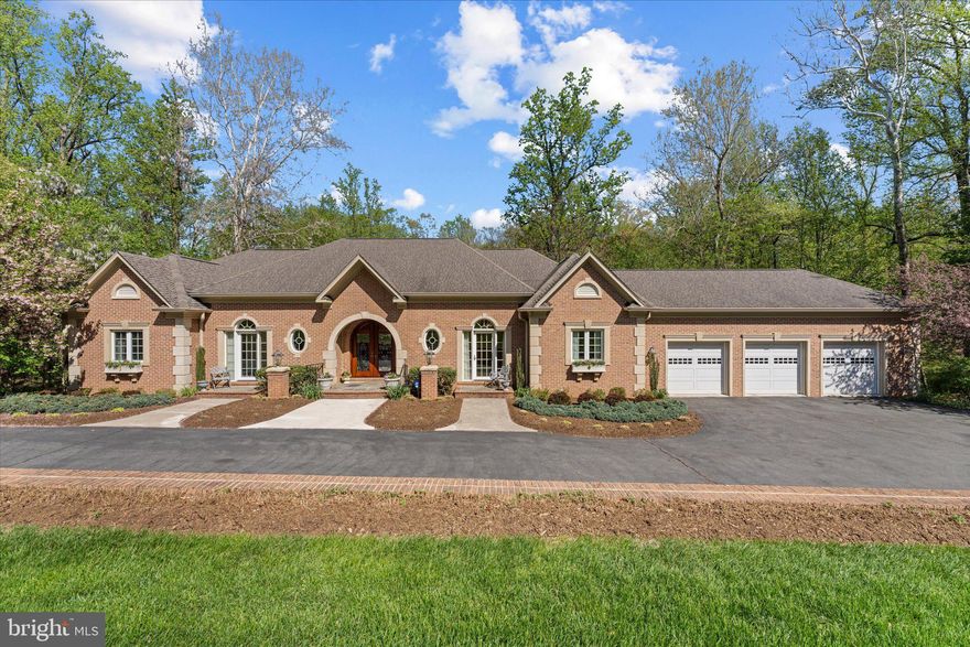 A home of quiet distinction and enduring elegance, this custom-built, 6200 sq feet  estate at 22030 Watson Road offers an exceptional blend of timeless architecture, refined craftsmanship, and serene privacy on a beautiful 3-acre parcel in Leesburg. Designed for the discerning buyer who values both luxury and livability, the residence showcases gracious main-level living paired with a fully independent lower-level suite—perfect for multi-generational living, extended guests, or a private retreat—complete with a spacious three-car garage.

From the moment you arrive, the home’s stately brick façade, arched entry, and custom 8-foot solid mahogany doors with leaded beveled glass set a tone of sophistication. Professionally landscaped grounds, enhanced by subtle evening illumination and thoughtfully engineered drainage, create a lasting first impression while ensuring long-term ease of maintenance.

Inside, the main level unfolds with expansive, light-filled spaces designed for both everyday comfort and elegant entertaining. Soaring 10- and 9-foot ceilings, extensive crown molding, custom millwork, and designer chandeliers lend warmth and architectural richness throughout. The main level features four spacious bedrooms and three full bathrooms, offering true one-level living without compromise. Multiple French doors seamlessly connect the interior to a covered stone terrace—an inviting outdoor living room framed by architectural columns and tranquil wooded views, ideal for al fresco dining or quiet relaxation.

The heart of the home is complemented by custom cabinetry, oversized 36-inch doorways, deep windowsills, and flexible, non-load-bearing interior walls that allow for future customization. A private home office with its own exterior entrance and bath offers an ideal space for work or client-facing use. Two fireplaces—one gas and one wood-burning—provide both convenience and ambiance.

The expansive lower level is a standout feature, offering over 4,000 square feet of finished space, including a fully self-sufficient in-law or guest suite with private entrance, full kitchen, living and dining areas, two bedrooms, and one and a half bathrooms. A separate HVAC zone and enhanced sound insulation ensure comfort and privacy between levels, while abundant storage and thoughtful details—such as a bar area and future fireplace rough-in—add versatility and comfort.

Constructed with enduring quality in mind, the home features solid brick exterior walls, 2x6 framing for superior insulation, aluminum-clad windows with Low-E glass, powder-coated iron railings, and a buried 1,000-gallon propane tank with owner-controlled supplier flexibility. Energy efficiency and low maintenance were paramount in the design, with gutter guards, underground drainage systems, solar-powered lighting, and a direct propane line to the outdoor grill further enhancing convenience.

Complete architectural design and construction drawings will convey at settlement, offering a rare opportunity to fully understand and appreciate the thoughtful planning behind this exceptional residence.

A property of substance and sophistication, this is luxury living defined by quality, flexibility, and timeless appeal.