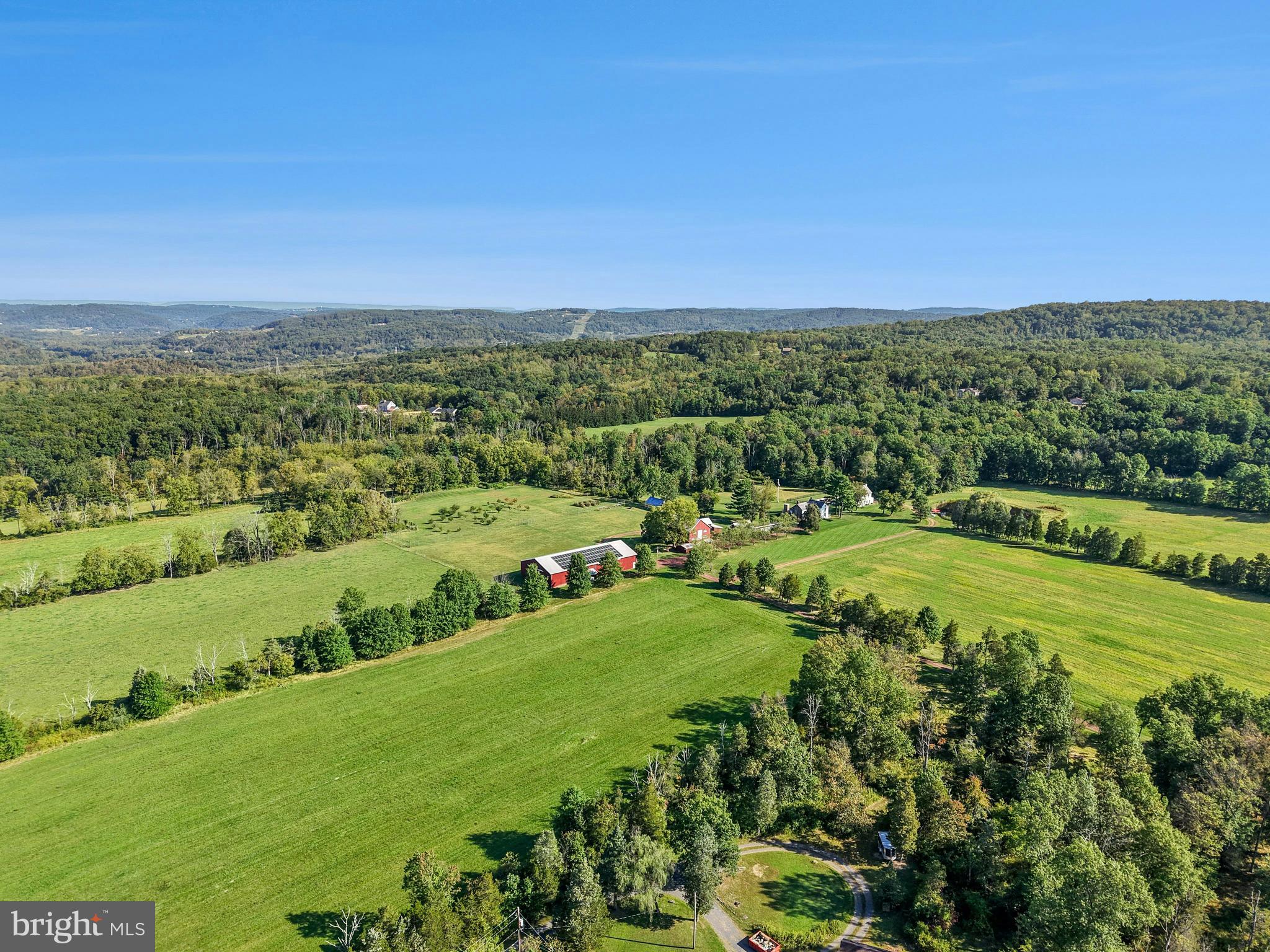 Bucks County farmhouses are defined by their settings and their position on their acreage, overlooking their fields and pastures, with long driveways leading past bank barns and farm buildings. Wheaton Fields Farm is one of the finest examples of these storied properties, boasting 50 acres of woods, fields, pond and even an orchard.
At Wheaton Fields, approach to the cluster of picturesque farm buildings is down a quarter mile drive, nicely removed from a quiet country road. The quintessential 1800’s pointed stone colonial, with rocking chair front porch, has been renovated and enhanced. A 2024 great room addition has three walls of glass, an exposed stone wall, wet bar, skylights, and fireplace, all opening to the sandstone patio with long distance views over the acreage and beyond. Pine, hickory and tile floors span both levels of the home. Throughout, 3 fireplaces, mullioned glass windows with deep windowsills, and period hardware attest to the classic Bucks County farmhouse character. Completing the first floor is a cozy living room with fireplace, dining room and charming country kitchen. On the second floor, there is an open and airy primary suite, bath and two additional bedrooms.
Outside, there are multiple buildings that have been cleverly converted into areas for guests, family, or hobbies. A picture-perfect 2017 pool house was designed to complete the original farmhouse with its own stone exterior. The stunning kitchen and great room with radiant heated floor opening to a covered patio and heated saltwater pool overlooking the orchard and greenhouse. Upstairs, a full bath and two additional studio rooms make this an ideal space for visitors. Nearby, one of the original farm buildings now boasts 3 charming cottages, 2.5 baths, as well as a family room, kitchen and laundry facilities. The three story bank barn includes a wing that has been converted into a studio, with bath and kitchenette. The 2015 pole barn will store every toy and farm essential and has solar panels sufficient to run the whole property. The private pond and dock beckon an afternoon on the water. Finally, there is a greenhouse and a fenced orchard with mature apple, pear, peach and plum trees.
This solar-powered property with generator lets you relax and invite a crowd for summer weekends, winter escapes, and every holiday. Whether a full-time residence or a weekend retreat, special occasions and other outside events will be celebrated here with joy. The views from the porch and patios provide an ever-changing panorama of seasonal colors and simple evening relaxation under the stars.
Wheaton Fields is the perfect farm property, enhanced by elements from a bygone era and nestled in a secluded Bucks County setting. This clever design allows for use as a family compound or for multi-generational living. This private paradise loses touch with the world just over the hills, yet is still within easy driving distance to magic weekends of Bucks County dining, antiquing and recreation.