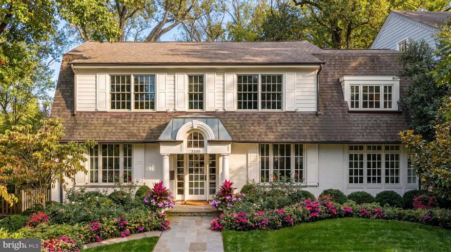 A spectacular Dutch Colonial in the heart of coveted Cleveland Park, Newark Street NW is a home for the true connoisseur. Originally built in 1920 and meticulously reimagined a century later, with thoughtful improvements since, the residence is set on a prized and beautifully landscaped lot along one of the neighborhood’s most distinguished streets. It embodies a perfect harmony between historic charm and contemporary sophistication.

Approached by a central flagstone walkway or a discreet private driveway, the home’s first impression is one of sophisticated elegance. Beneath a welcoming portico, a glass front door opens into a central foyer with inlaid hardwood flooring, refinished throughout the home. Window seats with custom cushions are thoughtfully integrated throughout, creating charming moments for reading and relaxation. The interiors, professionally curated by Hudson Gray Design, offer a refined yet inviting aesthetic.

Formal living and dining rooms flank the entry in a classic center-hall configuration, each adorned with designer wallpaper by Phillip Jeffries. The living room is bathed in natural light from windows on three sides and centers around a newly added gas fireplace flanked by illuminated built-ins. The dining room, richly appointed for elegant entertaining, connects to the kitchen through a fully equipped butler’s pantry.

A central vestibule houses the main staircase, illuminated by a large bay window, and serves as the transition between the formal and informal living spaces. At the rear of the home, an open-concept kitchen and family room form a luminous and airy living area with seamless sightlines and abundant natural light.

The chef’s kitchen showcases two standout features: a sculptural custom hood and thick-edge quartz countertops on a large center island. Commercial-grade appliances, including a 48-inch Viking range, pair beautifully with gold fixtures, stacked cabinetry, and a full-height quartz slab backsplash. The result is a space that is both visually striking and highly functional.

The adjoining family room, anchored by a gas fireplace, features a collapsible glass wall that opens fully to the multi-tiered rear deck. This thoughtful design blurs the line between indoor and outdoor living, offering a tranquil setting surrounded by lush greenery.

Upstairs, the primary suite serves as a serene retreat. It includes two custom dressing rooms and a luxurious en suite bath clad in Carrara marble. The bath features a double vanity, freestanding tub, walk-in shower, private water closet, and radiant heated floors. Three additional bedroom suites, each with walk-in closets and en suite baths, complete the upper level; one secondary suite also includes a custom desk and built-ins. A conveniently located laundry room is positioned nearby.

The lower level continues the home’s refined aesthetic with a spacious recreation room and full bath, an additional bedroom suite, and a well-appointed mudroom with custom lockers and a dog wash station. This level also provides direct access to the attached two-car garage, a rare and coveted feature in this exclusive neighborhood.

Smart home features include integrated speakers and custom window treatments with motorized shades. Outdoor living is equally exceptional, with a covered lower-level terrace and a newly added screened-in porch that is heated for comfortable four-season use, both overlooking lush landscaping and inviting hardscaping designed by Richardson & Associates Landscape Architects. The grounds gently cascade to a private flagstone patio with a gas fire pit plumbed to a dedicated gas line for effortless, regular use, while the grill on the upper deck is likewise connected to a permanent gas line.

Finished to the highest standards both inside and out and ideally located in one of Washington’s most desirable neighborhoods, Newark Street NW stands as a rare and timeless example of classic design reimagined for modern living.