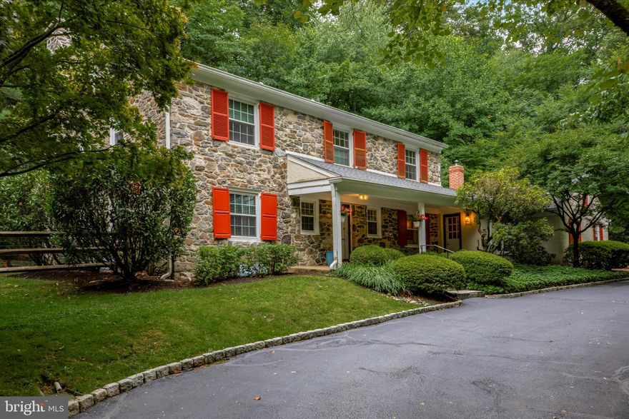 Nestled on a serene 1.18 acre wooded lot in Bryn Mawr, sits this beautiful 4 bedroom, 3 and a half bath Stone Colonial.  As you enter from the welcoming front porch, you will immediately notice the gorgeous hardwood floors that flow throughout this 3,662 square foot home.  To the left of the center hall is the office/study with custom bookshelves which are perfect for booklovers or collectors.  Head into the large formal living room where you will be captivated by the huge window that brings the outdoors in and creates a peaceful ambiance along with the wood-burning fireplace.  From here the large formal dining room with crown molding and chair rail is ready to host dinner parties both large and intimate and opens to an oversized lovely brick patio.  The chef’s kitchen does not disappoint with top-of-the-line stainless steel appliances, granite countertops and a huge island space that flows into the cozy family room with vaulted beamed ceiling, and an exposed brick wall with a wood burning fireplace.  A mud/laundry room sits conveniently off the family room and gives access to both the tranquil back patio and the garage.  A half bathroom completes this level.  Upstairs, the primary bedroom suite offers 2 closets and a full ensuite bathroom.  There is a second bedroom with a full ensuite bathroom, 2 additional bedrooms and another full hall bathroom with a soaking tub.  Sizeable bonus walk up attic offers an option to use as a den or storage space.  The finished lower level offers additional living space for a playroom or gym.  There is an attached 2 car garage and additional parking.  The lush grounds offer both a level fenced-in yard as well as open wooded area with a stream home to blue birds, cardinals and red belly woodpeckers for the nature lover.  There is a large storage shed/bomb shelter.  This home features a new roof, fireplaces, windows, and sump pump.  Located in the award-winning Lower Merion School District.  Close and walking distance to shops, restaurants, the train station, Bryn Mawr Hospital and major roadways.  Your private oasis awaits.