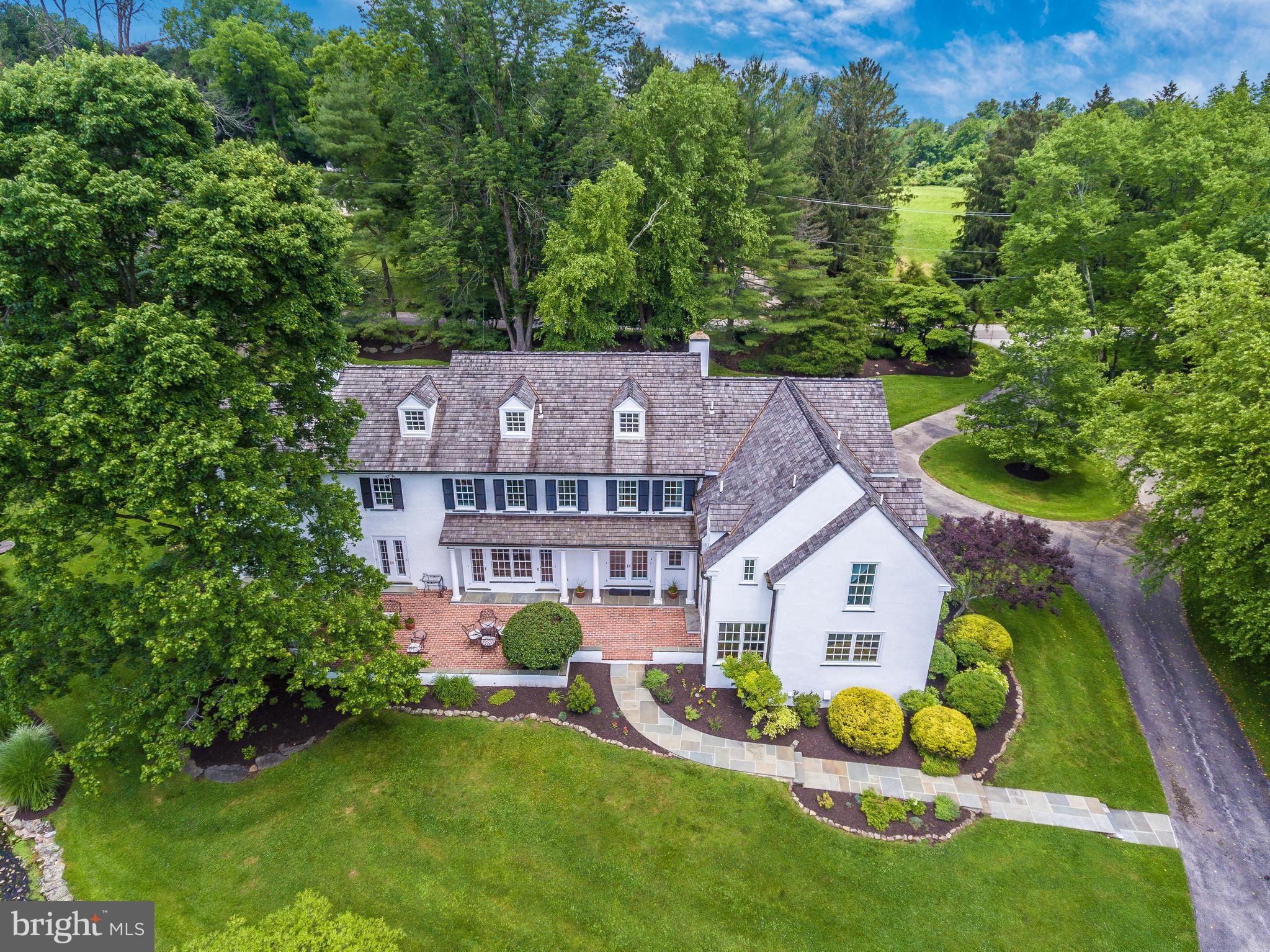 Homes seduce with their character and charm. This home with it's gardens and lush greenery embraces that allure. It is situated in the center of 5 acres in the prestigious Easttown Township on sought after Buttonwood Road. It has it all - privacy yet a sense of community, minutes to shopping, restaurants and transportation. Relax in this tranquil home knowing the bustling city is a short drive away. Additionally, New York, Baltimore and DC are all a quick Acela train ride away and the airport a short 25-30 minute ride away.
Attention to detail is immediately evident upon entering the foyer which provides a peek at the grounds behind the home. You are greeted by a terra cotta tile floor, two coat closets, a dry bar and a powder room. A handsome library/study with built ins and a wood burning fireplace are just off the foyer. Enjoy the graceful dining room with a large window and french doors that spill onto the brick patio set to entertain and overlook the pond and sweeping back yard. The large living room complete with french doors also spilling to the brick patio has sizable windows providing ample natural lighting and beautiful views of the front and back outdoors. With plentiful windows and french doors the music room is the perfect space to perfect your musical talent or to relax and listen to your favorite music. A very functional mudroom and laundry room are off the sunlit back entry which includes french doors . A powder room and a spacious media room with built ins and a bank of windows to enjoy the outside views awaits at this end of the home. Through the banks of windows in the kitchen and breakfast area you will enjoy welcoming the morning sun. It is a perfect spot to enjoy a cup of coffee and your casual meals. The kitchen is stocked with a gas cooktop, stainless steel double ovens, and designer cabinetry. You can be prepared for the unexpected by stocking up on goods and storing them in the walk in pantry.
Gentle rays of sunshine fill the second floor hall that connects the five bedrooms. The large primary bedroom has a wood burning fireplace and adjoins with the large master bath with a double sink vanity, a dressing vanity and a soaking tub. Pull the plug on stress and slip into serenity while enjoying the natural lighting provided through the palladian window. The walk in custom closet will divide your clothes neatly and can be accessed through the bedroom and the bath.
Four additional bedrooms , all with their own baths and an office complete this floor. All rooms have large windows and stunning views of the outdoors. If you like, you can burn the midnight oil and get that extra work finished in the home office while still in close proximity to the bedrooms.
Can't see the sun? You can still have fun in the spacious play room on the third floor.
Enjoy this private oasis from the lovely pool and poolhouse complete with a powder room, dressing room and kitchenette where you will whip up delicious snacks and beverages for you, your family and guests to enjoy.
