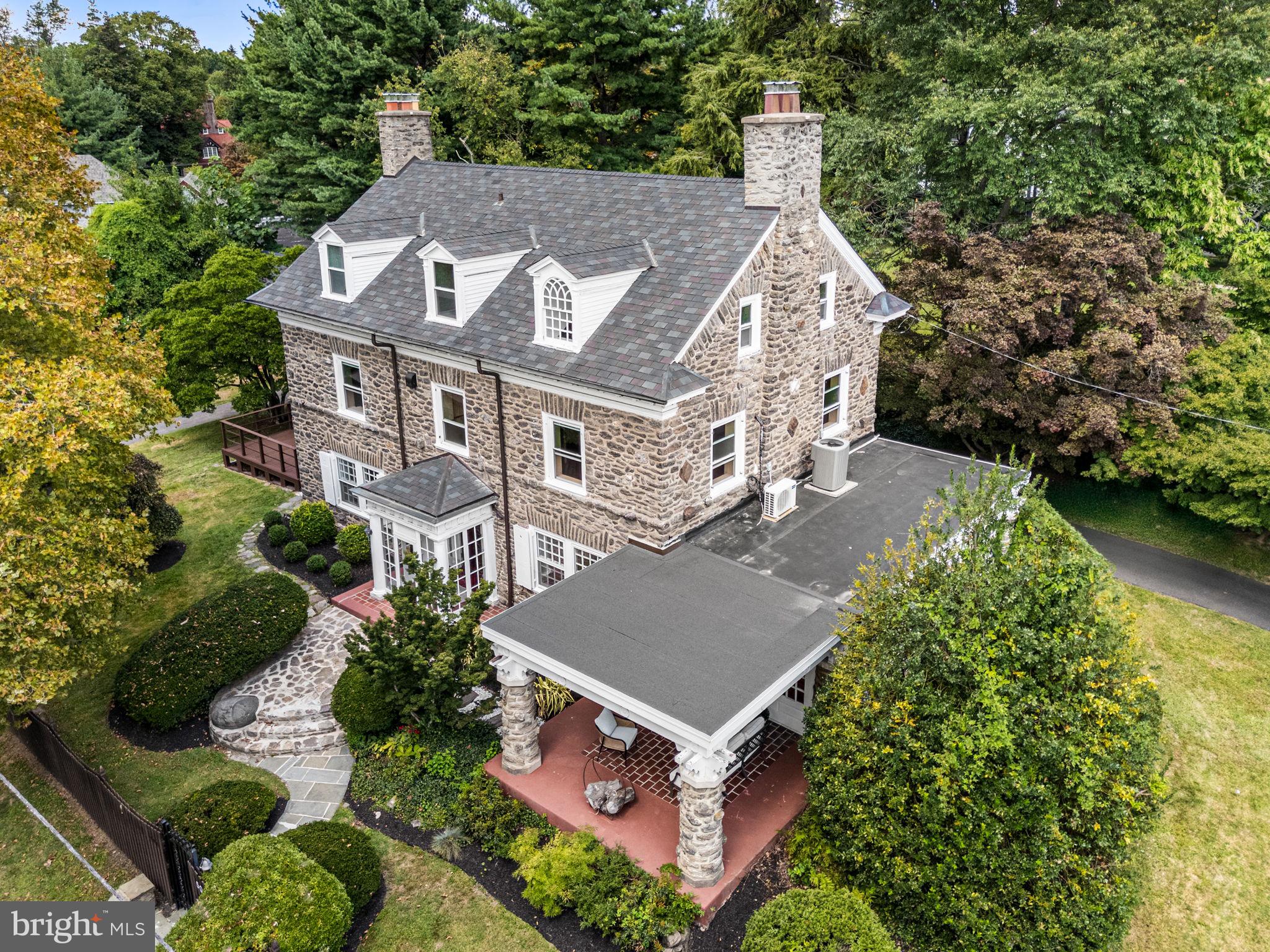 Situated on a beautiful half-acre corner lot in desirable and historic Mount Airy, this distinguished five-bedroom, four bathroom residence was built in 1925 and has been meticulously updated for contemporary living. The home's stately Wissahickon schist façade, charming front porch, and ornamental windows speak to a bygone era of craftsmanship, while its thoughtful renovations make it ideally suited for today’s lifestyle. Mature plantings, lush gardens, and manicured grounds enhance its distinguished curb appeal. A circular drive leads to an oversized, detached two-car garage, ensuring abundant off-street parking. A large deck directly off the kitchen provides the perfect setting for al fresco dining or entertaining.
Inside, a bright center hall welcomes you with rich millwork, intricate moldings, and original newly refinished original hardwood floors, including striking herringbone on the main level. The expansive chef’s kitchen features custom cabinetry, high-end stainless steel appliances, abundant storage, a large center island and room for a table and chairs. Entertaining spaces include a stunning dining room with oversized windows, designer finishes, and a grand fireplace, as well as a spacious living room with a second wood-burning fireplace. Two separate sets of French doors open into a sun-drenched sunroom with a third fireplace, while a covered side porch offers yet another space to relax or entertain.
Upstairs, the luxurious primary suite occupies nearly half of the second floor, offering three walls of windows, a vanity area with dual closets, and a custom walk-in dressing room with center island. The en suite marble bath features an oversized walk-in shower and soaking tub. An additional bedroom suite with full bath completes this level. The third floor includes three more generously sized bedrooms, one of which features custom built-ins—ideal for a private study or home office.
A fully finished lower level offers extensive recreation space including a full bar, a sauna with adjacent steam shower, and plenty of room for gathering or unwinding.
Enjoy the best of Mount Airy living with a short walk to SEPTA’s Sedgwick Station for an easy commute to Center City. Chestnut Hill, Manayunk, and the Main Line are just minutes away, while Wissahickon Valley Park offers miles of wooded trails for hiking, biking, and horseback riding. Stroll to neighborhood favorites like Weavers Way Co-op, Mount Airy Village, cafés, restaurants, parks, shops, and the public library. This home delivers the perfect balance of urban accessibility and natural serenity—truly the ultimate in location and lifestyle.
This is more than a home—it’s a piece of Philadelphia’s architectural legacy, thoughtfully revitalized for modern living.