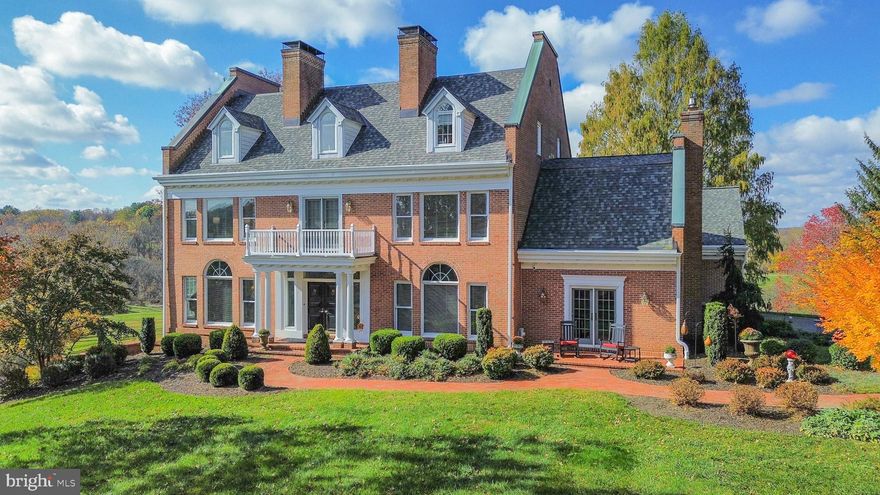 Stately all-brick colonial in the prestigious Lambourne Downs / Western Run Valley community, offering approximately 8,500± sq. ft. of finished living space on 4.6± scenic acres. Boasting exquisite curb appeal with professional landscaping, brick paver walkways and patios, covered front porch, side-load 2-car garage, ample off-street parking, updated architectural shingle roof, and sweeping views of the valley.

Step inside the grand marble foyer showcasing crown, dentil, and chair rail moldings, wainscoting, wall sconces, fireplace, and a stunning curved staircase. The living room off the foyer offers hardwood floors, dentil crown molding, chair rail, wainscoting, and fireplace, opening to the professional office with hardwood floors, crown and chair rail molding, wainscoting, built-ins, niche, and slider access to a covered rear deck overlooking the tranquil setting.

The gourmet eat-in kitchen features hardwood floors, granite countertops, a center island with breakfast bar, recessed and pendant lighting, soft-close cabinetry and drawers, built-in pantry, and a coffee area with glass-paneled cabinetry. Built-in appliances include a side-by-side refrigerator, wall oven, built-in microwave, electric cooktop, and range hood. The adjoining breakfast area with cathedral ceiling provides access to the rear deck, ideal for morning coffee or casual dining.

Off the kitchen, the enormous great room impresses with hardwood floors, crown and chair rail moldings, wainscoting, gas fireplace, wet bar, access to the garage, and access through a sliding glass door to one of the beautiful brick paver patios. The formal dining room is equally elegant with hardwood floors, dentil crown molding, wainscoting, fireplace, and a stunning Palladian window. The main level also includes a dual-access powder room and second staircase to the upper level.

Ascend the curved staircase illuminated by a chandelier to the luxurious primary suite offering a fireplace, crown molding, carpet flooring, massive walk-in closet with balcony access, and a fully updated ensuite featuring frameless glass shower, clawfoot soaking tub, water closet, and dual granite vanities—one with extra storage and one with dressing area. The upper level continues with a dual-entry full bath, second bedroom with double-door closet, third bedroom with fireplace, crown molding, and double-door closet, laundry room, and fourth bedroom with private ensuite bath.

The top level hosts a sprawling bonus room with carpet flooring, dormer windows, ceiling fans, zoned HVAC, walk-in closet, and access to an exercise room—perfect for recreation, hobbies, or studio use.

The multipurpose lower level includes fifth and sixth bedrooms (one carpeted, one tile), full bath, utility room, recreation room with fireplace and full stone hearth, recessed lighting, and tile flooring, plus a game room with slider to the covered rear patio.

Outdoor living is extraordinary with a composite rear deck with vinyl railings and awning, covered patio with additional storage, three brick paver patios, and a charming covered front porch—all surrounded by tranquil valley scenery.

Additional highlights include three-zone HVAC, exceptional craftsmanship, and numerous high-end upgrades throughout. Combining timeless architecture, luxurious finishes, and peaceful surroundings, this remarkable estate offers an unparalleled living experience in one of Baltimore County’s most sought-after locations.