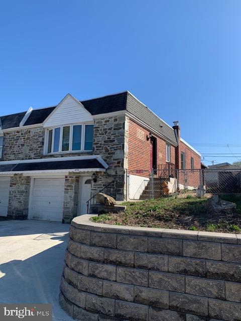 Here's a winner. Solid built stone & brick twin rancher on desirable street in the Upper Roxborough neighborhood of Philadelphia. The home offers a lower level that contains a built-in garage, laundry/storage room (could be a 2nd kitchen location), a super large bedroom suite with beautifully tiled private bathroom that includes a zero entry shower, storage closets and a rear exit to a covered patio complete this level. The upper level offers an L shaped open living/dining room w/vaulted ceiling, a spacious eat-in kitchen with an abundance of cabinetry, gas cooking & dishwasher, a hall closet, the 2nd bedroom w/closet, an updated hall bath w/skylight, a linen closet, and the enlarged main bedroom (2 bedrooms were combined to make the main) w/closet. There is a fenced side & rear yard with a handsome retaining wall in the back of the yard. The front driveway was enlarged to accommodate 2 car parking. Sper convenient location within walking distance of the IvyRidge Shopping Center (Neighborhood Target w/CVS & Starbucks, Pa. Spirits store, Popeye's, Pizza parlors, DD, and bus stop), Shoprite grocery store and the YMCA. Enjoy the wonders of the nearby Wissahickon Park trails and the public Walnut Lane Golf Course.