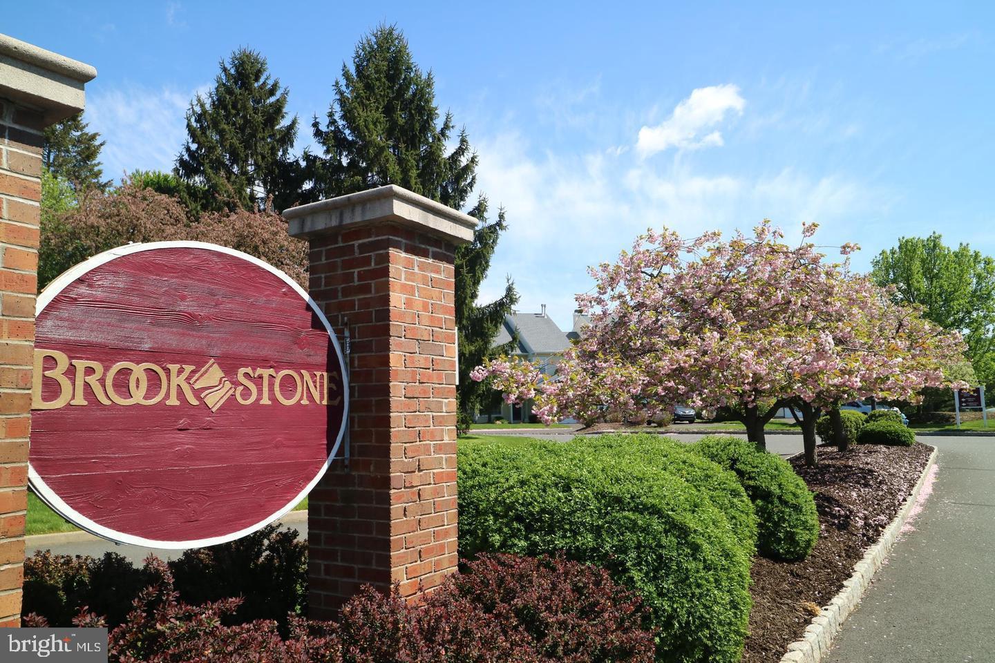 Welcome to your new home!  A lovely 2nd floor 3 bedroom, 2 bath and one car garage corner unit in beautiful Brookstone community. The sun-drenched upper level condo has a spacious cathedral ceiling living and dining room with custom plantation shutters, recessed lighting, hardwood floors, a wood burning fireplace and a balcony that overlooks the community open space. The kitchen features gas stove, newer appliances, ample counter and cabinet space and a breakfast area surrounded by windows. The primary bedroom has a  vaulted ceiling, walk-in closet and ensuite full bath with dual vanity, jacuzzi tub, stall shower and skylight. The front second bedroom down the hall has windows and closet. The 3rd bedroom is off the living room with windows next to the deck along with French door access to the living space, so could also work very nicely as an office if you chose to do so. Convenient laundry/utility room with shelves and  coat/storage closet are in the hallway. Purchase of home includes a 1 year home warranty from Cinch so you can buy with confidence.  You are a short walk to clubhouse and pool or the tennis courts or basketball courts. Easy commute to Philadelphia and NYC, Truly an amazing home.