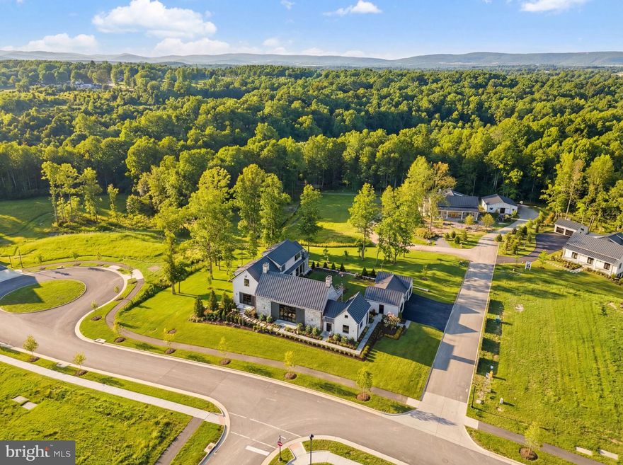 Nestled within the prestigious Residences at Salamander, this newly constructed, custom-expanded Stables Deluxe floor plan occupies one of the most desirable settings in the community—a high-elevation corner lot in the Stables (Lot 38). Notably, it is one of the larger lots and positioned above many neighboring homes, offering enhanced privacy, presence, and long-range serenity among mature trees. This exceptional four-bedroom, four-bath, two half-bath residence spans approximately 7,900 square feet of total living and potential space and is currently the only move-in-ready home available in the Stables section of the community, a rare and compelling distinction. The striking stone façade and custom-designed two-car garage with porte cochère—an upgrade beyond the standard offering—create an elegant and substantial arrival.

Inside, the home unfolds with effortless flow and inviting warmth, elevated by premium materials and finishes selected well above the builder’s baseline throughout. The main level has been thoughtfully expanded to include a side-load entry, service powder room, and enlarged mudroom, complemented by a spacious laundry room and a beautifully integrated wine cellar and pantry. Wide-plank French oak floors and refined custom millwork set the tone, while the chef’s kitchen anchors the home with Wolf, Sub-Zero, and Cove appliances, custom cabinetry, bespoke countertops, and a dramatic full-wall backsplash behind the island—perfectly balancing everyday functionality with elevated entertaining.

The primary suite is a true retreat, generously enlarged to include a cozy sitting area with fireplace and direct access to the courtyard. Its spa-inspired bath showcases heated floors, custom cabinetry towers, designer wall coverings, a luxurious his-and-her wet room, and exquisite marble detailing. The primary closet, complete with a built-in wall safe, blends elegance with practicality. All additional bedrooms are spacious and feature their own ensuite luxury full baths, including two located on the upper level, ensuring comfort and privacy for family and guests alike.

Beyond the home itself, this residence delivers a lifestyle that is both refined and convenient. Enjoy walking distance to the historic charm of Middleburg, easy proximity to Dulles Airport, and exclusive access to Salamander Resort’s world-class amenities, including acclaimed dining, spa and wellness experiences, equestrian offerings, and curated social events—all while enjoying the added distinction of a larger, elevated Stables lot that sets this home apart from the Vineyard section.

This is a rare opportunity to own a bespoke, move-in-ready residence on one of the most premium lots within the Residences At Salamander, where elevated design, superior materials, and unmatched setting converge to offer not just a home—but a truly exceptional lifestyle.