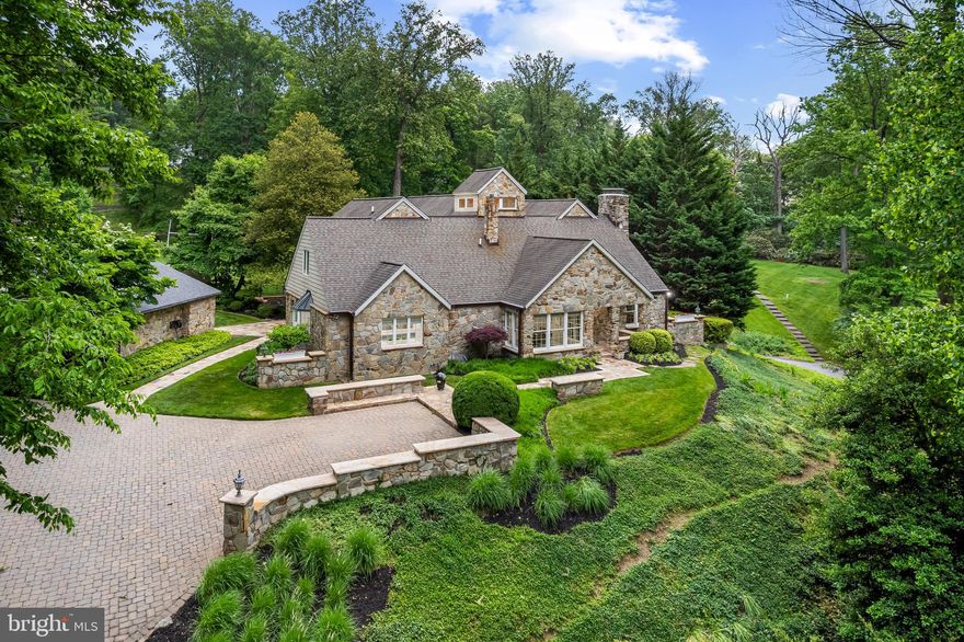 A long drive leads to an exceptional private retreat on 2.8 acres - a remarkably stylish Craftsman-style Butler stone residence surrounded by mature trees, gardens, and rolling lawn. Reverse the clock thirty years as new buyers begin transformation and expansion, then fast forward to find beautifully designed grounds and a home drenched in warmth with meticulously crafted updates and architectural elements, fine millwork and finishes, high-end systems, four fireplaces and a seamless blend of traditional elegance and contemporary design. Formal and casual spaces filled with natural light are open, airy, and in harmony with the pastoral esthetic. The rustic stone woodburning fireplace is the focal point of the great room with display cabinetry, an entertainment center and wet bar with beverage drawers adjacent to the spacious dining room. The living room with second woodburning fireplace opens to a handsome study with mahogany built-ins and an impressive stone wall. In a separate wing on the main level is a large bedroom and 2021 bathroom created for guests and currently serves as a second family room area. The stunning 2022 white and soft blue chef’s kitchen with butler's pantry and wine refrigerator features quartz counters, a Wolf 6-burner dual-fuel gas range with pot-filler, wall ovens, warming drawer, a SubZero refrigerator, and a separate SubZero freezer. A large island with breakfast bar and unique ambient lighting anchors the space, just steps from the breakfast room and mudroom with cubbies for school and sports gear. Upstairs, the spacious owner’s suite offers a tray ceiling, gas fireplace, walk-in closet, and a 2021 luxurious marble bathroom with a soaking tub, steam shower, and sauna. Off the second level sitting area with vaulted ceiling and dramatic windows are three additional bedrooms, two new 2021 marble baths, and a conveniently located laundry area. The lower level includes a fitness room, theater room, home office, workshop, utility area with a Viessmann boiler, and a sixth bedroom with a wood stove and full bath - ideal for an au pair or guests, with direct outdoor access. Car enthusiasts will appreciate the two detached garages, while gardeners will enjoy the tool and potting room, three-bay equipment shed, and fenced kitchen garden. Other notable improvements include a 2023 40-year roof on the stone garage, a 2016 40-year roof on the main residence, 2022 copper gutters and downspouts, a 2026 Viessmann boiler controller, 2025 Ipe decking and lighted railings, a 2014 septic system, and 2025 security and intercom systems. Additional features include 9-zone central air, 11-zone heating, a sound system, and extensive landscape, hardscape, and fencing installations. Savor the opportunity to be a magnet for year-round gatherings and recreation. Imagine warm evenings practicing your putts on the green to a trill of peepers or settle back on the beautiful Brazilian walnut deck to enjoy sunset as little feet cross the lawn to climb the tree house or field a lacrosse ball. The setting is unique, private, and picturesque, yet just minutes from I-695, schools, Towson Town Centre, and Baltimore’s vibrant Inner Harbor.