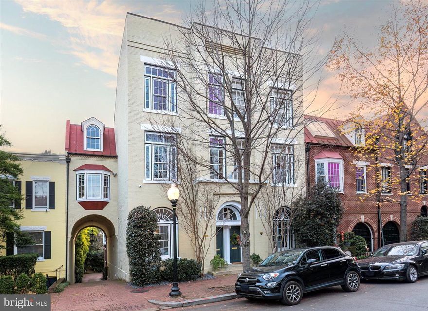 MAJESTIC GEORGETOWN RESIDENCE WITH A RICH HISTORY! This impeccably renovated residence, originally built in 1891 at the turn of the 19th century, 3220 Volta Place remains a historic landmark in the heart of Georgetown. First built as an Officer’s Club and later serving as Washington’s 7th Precinct Police Station, this imposing structure was later converted into two residences by renowned architect Robert A. Bell. The façade of the building remains unchanged from a century ago, with thoughtful details, including the fanlight windows and flagpole retaining their historical origin. 

With over 5,000 square feet of exquisitely finished space that was recently renovated spread over 4 levels with soaring 13-foot ceilings, wood floors in every room, numerous natural gas fireplaces, expansive windows that sit high above the street for privacy, skylights for bright natural lighting throughout, large hall and bedroom closets providing abundant storage solutions, all floors connected by an elevator, built-in stereo-system on every floor, and impeccable sound insulation providing peace and quiet from the activity of Georgetown. A rare find in Georgetown and is ideal for intimate gatherings and large-scale entertaining. 

The five-bedroom corner exposure Georgetown residence includes an attached garage and semi-private motor court. 3220 Volta Place is located on one of the most beautiful streets in Georgetown across from the National Conservatory of Dramatic Arts and steps away from Georgetown’s Volta Park which features a dog park, basketball courts, swimming pool, and picnic areas. 

On the first floor, The entry foyer is a grand space with 13’ ceilings that opens to a grand receiving room or dining space with a chandelier. The hallway leading to the kitchen has a powder room for guests, shoe closet, and coat closet. The chef’s kitchen includes floor-to-ceiling custom cabinetry, a large marble island, a fireplace, and Miele appliances, and large skylight. Beyond the kitchen, French doors open to a wood-paneled atrium with multiple skylights and a full wall of windows that open to create a private courtyard for open-air summer entertaining. Beyond the atrium, is a cozy family room with built-ins, hidden refrigerator, entertainment area, and a large bay window overlooking the rear semi-private courtyard. Above the family room, a private guest room with a renovated en-suite bath provides guests a secluded oasis while visiting. 

Second Floor: At a delightful twenty-five feet in width, the second floor sitting room has floor-to-ceiling arched windows overlooking a semi-private courtyard pouring natural light into the main living room. With a large fireplace, built-ins, and an adjoining room with a wet bar, it’s fair to say this room is both grand and cozy at the same time. The exceptionally appointed wood-paneled library is a few steps away, which makes the perfect home office complete with a private bath or the ideal setting for a book or art collection. 

Third Floor:The primary bedroom suite, on the third level, is a sanctuary of peace and tranquility. The bedroom has cathedral ceilings and a south-facing bay window overlooking the semi-private courtyard below. There are two large walk-in closets, a fireplace, and a spa-inspired en-suite bath with heated floors, dual vanities, a frameless glass shower, and separate soaking tub. An additional bedroom with beautiful built-ins and en-suite bathroom completes this level. 

On the lower level, there is a one-car attached garage with access to the shared motor court. The lower level features a bedroom with an en-suite bath, a large in-home gym, a spacious laundry room with built-ins, an additional full bathroom, ample storage, two washer/dryer units, a second full-size refrigerator, and 100-bottle wine refrigerator. 

The grand Georgetown residence is fully renovated & move-in ready with a location that could not be more ideal.  Also available for rent!