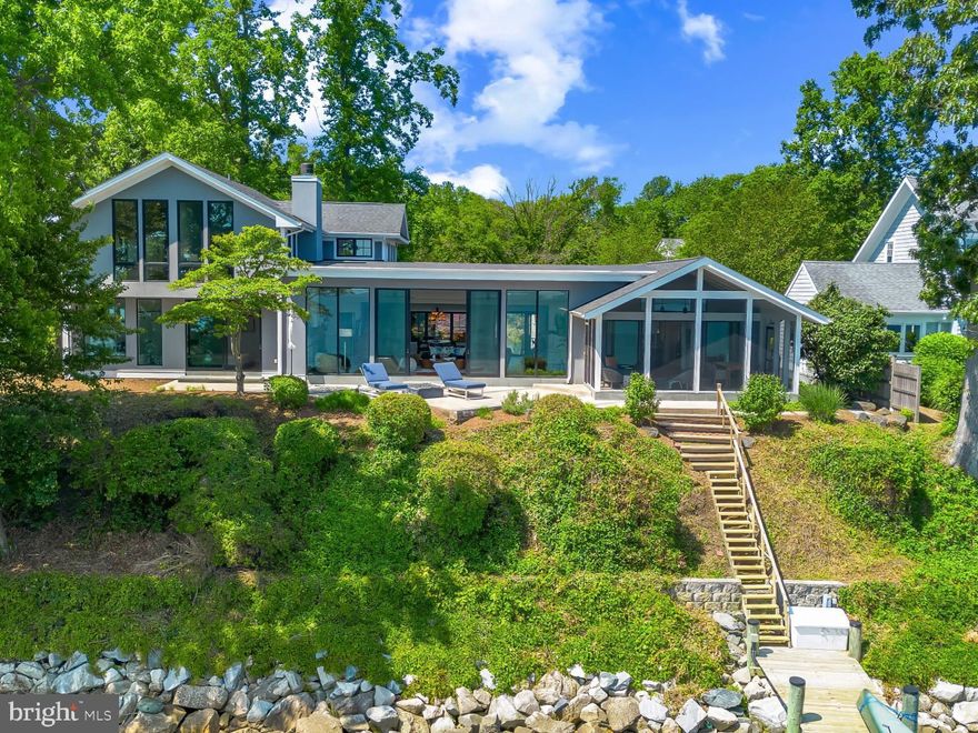 Life will never be the same.  This slick and sleek coastal contemporary is beautifully designed for optimal waterfront living.  With six bedrooms (FIVE ensuites), six full baths and one half bath, waterviews are visible from nearly all living spaces and bedrooms (and three bathrooms, to be fair).  Witness the walls of windows on the first level, facing the Chesapeake Bay to the East and Severn River to the Northwest; one will never be bored with the marvelously incessant theatre of watercraft and nature.   Enjoy morning coffee out on the open air patio, down at the pier, or in the large, screened porch.  If weather is uncooperative, stretch out in the massive open living area, or retreat to one of two second floor water-facing rooms (one perfect for sitting room/office) to take in a new perspective.  This home was fully renovated in 2017, sporting gorgeous custom light cherry 5" wood floors on the first and second level and showcasing unique custom, open staircases with black cable handrail system.  There are two primary bedroom ensuites; one on the first floor featuring concrete shower floor, bathroom floor and cast concrete countertop.  With generous, custom closets and oversized windows featured in each room, both residents and guests are guaranteed to render a five star rating for their stay and experience.   This property is one block from 70 acres of walking trails and two blocks from the community beach, playground, picnic pavilion and firepit.
