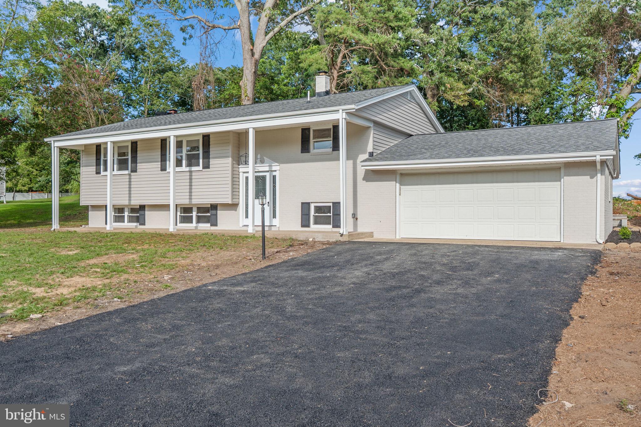 Fully renovated from top to bottom, this spacious 5-bedroom, 3-bathroom split-level home offers over 2,200 square feet of beautifully finished living space across multiple levels. The main level features a bright open floor plan with wood floors throughout, a stylish electric fireplace set against a custom wood-paneled accent wall, and a spacious kitchen outfitted with stainless steel appliances, ample cabinetry, and a dining area with French doors that open directly to a large deck overlooking the expansive backyard—perfect for entertaining or relaxing outdoors. The bedrooms are well-sized and feature custom wall trim that adds a refined, designer touch. All bathrooms have been thoughtfully updated with custom marble finishes for a spa-like feel. The lower level includes a large living area with a second fireplace, two additional bedrooms, a full bath, and a kitchenette area with a refrigerator and a large island designed to accommodate seating and entertaining—ideal for guests, gatherings, or multigenerational living. This turnkey home blends modern design with flexible functionality and outdoor appeal.
