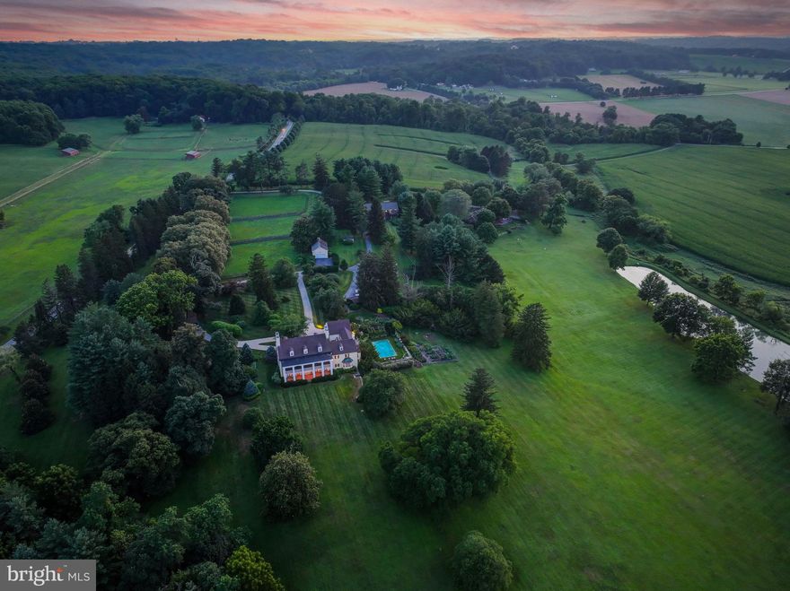 Live authentically. Montmorenci | Circa 1741. Built by Samuel Worthington. Commanding views overlooking Worthington Valley, Montmorenci is a storied estate steeped in history. Revel in the sense of arrival as you meander the tree-lined drive. The welcoming crunch of gravel in the roundabout as you step to enter.  A grand living hall whets your appetite for what's to come. Feel the difference that balanced proportions and the layering of a timeless European aesthetic can make in your daily life. Original details intact. Exceptional handcrafted millwork lends grace and depth to generous, light-filled rooms designed for living and gathering. Relish the farm to table healthy lifestyle... vegetables and herbs teaming with flavor picked directly from your garden. The chef’s kitchen invites connection, anchored by a fireplace and glorious views of the pond in the distance. Entertain effortlessly. Experience functionality and flow that has been meticulously designed for gatherings both intimate and large.  A handsomely appointed library awaits your collected volumes and curiosities. A significant architectural, sculpted mahogany staircase rises with grace. The primary suite, sumptuous and rich in detail, opens to an expansive terrace with sweeping views, while the spa-like bath offers fireside soaks and a moment to exhale. Separate primary suite baths, each with it's own distinctive personality and vista. Each secondary suite exudes exemplary style and unique character. 
Flow through the multi-purpose loggia to the sweeping gardens and curated grounds, where nature delights at every turn. Glass doors reveal landscaped terraces, verdant gardens, and the serene rhythm of nature. Lounge poolside and imbibe beneath the cross vine covered pergola, take in the clear skies and stars above as the evening settles in. Invigorate with sunrise laps. Charming pool-house tucked beneath the loggia. 
A fabulous brick barn, substantial stone tenant house, two apartments, a repurposed corn crib, and three pristine paddocks—cultivating a distinguished country lifestyle rooted in heritage. Comcast Internet. Cultivate your existence. The art of uniting human and home.