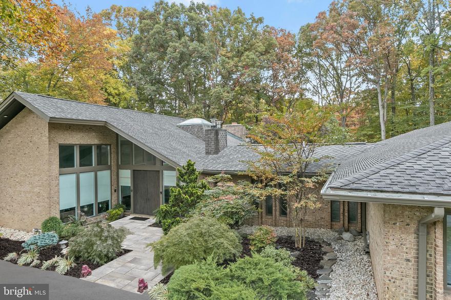 This stunning home has been beautifully and thoughtfully renovated creating abundant space for family living and gracious entertaining. There are high ceilings, walls-of-windows, a Zen garden, an invisible fence, and exquisite architectural details and a California contemporary allure. The welcoming covered entrance is a gateway to the impressive foyer with slate flooring, water feature complete with a koi pond and waterfall. The elegant main level boasts spectacular tile flooring, built-ins, coffered ceiling, and bucolic views. There is a formal living room and a formal dining room that are tastefully updated to create exquisite spaces that lead to the center of the home featuring a state-of-the-art kitchen and gathering space. The stunning chef's kitchen features two expansive center island, Leathered finish on Brazilian granite /quartzite with 3 inch bullnose, two sinks, a 48” wide refrigerator, top of the line Black stainless-steel high-premium Dacor appliances, a speakeasy walk-in pantry, ample inset cabinetry, built-in desk a second island with a beverage refrigerator, perfect for entertaining. The kitchen leads to a second more informal dining space for casual meals. There are two additional versatile spaces for entertaining - a second sunk-in living room and a built-in bar that is a throwback to the 70s. The generously sized main level hosts a primary bedroom suite featuring a luxurious marble bath, separate shower, his-and-her vanities, custom fit walk-in closets, complete with a wall to ceiling window that oversees a lushly landscaped Zen garden. There are three additional bedrooms and two full baths on the main level. Two bedrooms share a Jack and Jill bathroom. The homeowners have spared no expense to transform this home into a luxurious masterpiece on a 2+ acre private lot which is complete with a swimming pool and large front and back yards. The fully finished lower level hosts a butler’s pantry, a bedroom, a full bath, a large recreation room as well as a newly appointed yoga studio. There are endless possibilities for entertaining indoors and outdoors in this unique property that offers you, your own private Oasis with a beautiful pool and spa and handsomely landscaped grounds. Divine outdoor recreation extends on the multiple deck, a private overlook, pool deck and more.  Other amenities include a finished three-car garage, newly-renovated laundry room custom built-ins that follows the high-end theme commiserate with the finishes throughout the house. Upgrades include new roof, gutters, conversion from oil to electric, new HVAC systems, complete pool refresh including a subfloor, pool heater, retaining wall, flooring, windows, driveway, and so much more! Minutes to Potomac Village, this home is truly a masterpiece for a discerning buyer. Excellent school and a commuter’s delight!