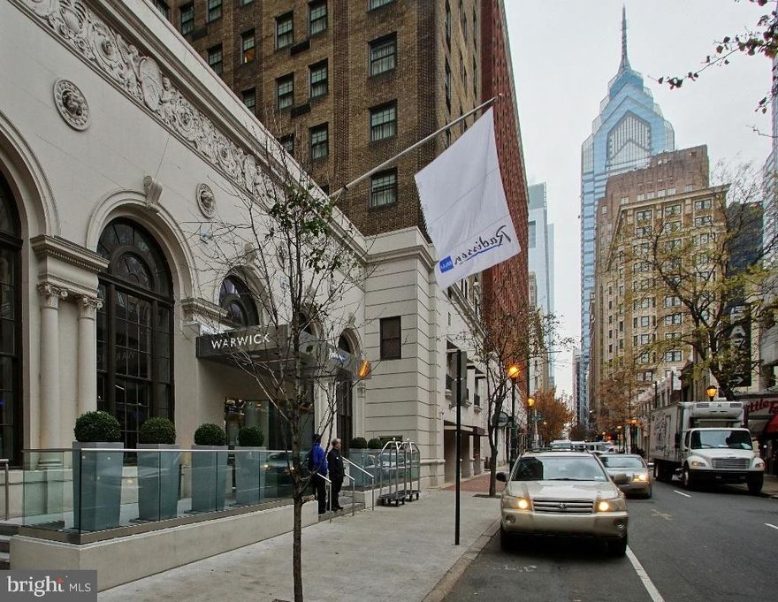 Rarely available and truly special, this expansive one-bedroom, one-and-a-half-bath residence at The Warwick Condominium offers 916 square feet of luxurious living with soaring ceilings, rich Brazilian Cherry wood floors, and custom painted walls, moldings, and millwork—all set against a breathtaking backdrop of the Center City skyline. As you enter, you're welcomed into a grand living and dining area that feels more like a townhouse than a condominium, where guests can enjoy the elegance of a beautifully appointed half bath with designer wallpaper and refined finishes. The spacious dining area easily accommodates a full dinner party and opens to an inviting  kitchen featuring rich wood cabinetry, stainless steel appliances, generous granite countertops, and a conveniently tucked-away washer and dryer. The serene bedroom suite boasts two windows framing the dazzling skyline, along with a fully customized walk-in closet that includes a makeup vanity and a hidden full-length mirror, while the marble-clad bathroom is a luxurious retreat complete with custom wall finishes and a tub-shower combo enclosed in seamless glass, offering the perfect end-of-day sanctuary. Perched just one floor from the top of this stately building—where the boutique condominiums occupy the upper eight floors—you’ll enjoy elevator access exclusive to residents and the lifestyle perks of hotel living, including a Bluestone Lane Café in the lobby and two of the city’s most beloved restaurants, Spice Finch and The Rittenhouse Grill. Parc, Via Locusta, and Almyra restaurants are  just steps away. With a fitness room, garage parking available on Chancellor Street providing direct entry into the building and a two minute walk to Rittenhouse Square, you will soon see why the residents consider this as Center City living at its most refined.