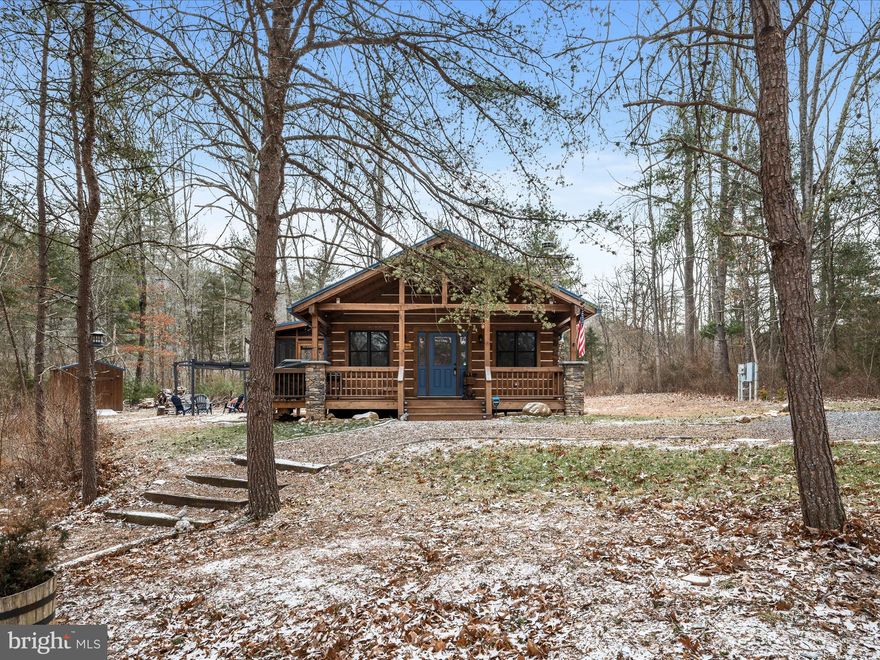 Escape to the serenity of this private log cabin retreat nestled on over 4 acres along the North River near Capon Bridge. Built in 2020, this 2-bedroom, 2-bath cabin feels like new and offers the perfect blend of rustic charm and modern comfort. Relax on the covered front porch or unwind on the screened side porch, taking in the peaceful wooded surroundings.
Inside, the open great room features a wood-burning fireplace, a well-equipped kitchen, and a spacious dining area—ideal for cozy gatherings. The primary suite includes an ensuite bath, while the second bedroom enjoys easy access to the hall bath. A dedicated laundry room with a tankless water heater adds to the home’s convenience.
But the real magic happens outside. With over 300 feet of river frontage, a charming wooded path leads to the water, where you can fish, kayak, or simply soak in the natural beauty. End your evenings by the fire pit and pergola, surrounded by the sounds of nature. A matching shed provides ample storage for outdoor gear and adventure essentials.
Located in a gated community within the Ice Mountain Nature Reserve, residents enjoy access to swinging bridges and scenic hiking trails. Please note: Short-term rentals are not permitted by the HOA, ensuring a truly peaceful retreat.
This turnkey getaway is ready to be your private escape—schedule a visit today!