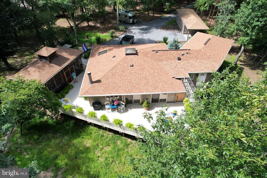 Tucked into a beautifully wooded 1-acre lot, this thoughtfully expanded 3-bedroom, 3-bath home blends natural serenity with comfort and character—and comes with access to the exceptional amenities of The Woods community.
There is ample outdoor entertainment space, highlighted by a detached screened pavilion, offering over 250 square feet of covered outdoor space with soaring ceilings—a perfect spot to unwind, entertain, or listen to the wind through the trees. Just steps away, a sprawling deck and outdoor shower enhance the peaceful retreat-like vibe.  
Inside, each bedroom is en suite, offering privacy and flexibility. One currently serves as a cozy den or TV room, framed by a striking wood and glass partition. The primary suite, a spacious addition to the original home, features a walk-in closet with laundry, a bonus room flooded with natural light from 8 Pella windows (ideal for a home office, sunroom, or reading room), and a luxurious bath with a luxury rainfall shower system in a beautifully tiled walk-in shower.
The main living area is open and bright, featuring a well-appointed kitchen, and a welcoming living room with wood stove.  Each area of the home is accessible to the large deck.   Upgrades in addition to the master suite expansion include upgraded bathrooms, flooring, counters and appliances.
Other highlights include extensive exterior lighting, a detached one-car garage with storage space and thoughtful updates throughout. As part of The Woods community, you’ll enjoy access to indoor and outdoor pools, a gym, tennis and pickleball courts, a spa, and more—all just minutes from your front door.
Whether you're looking for a full-time home or a weekend getaway, this property offers a lifestyle that feels both grounded and elevated.