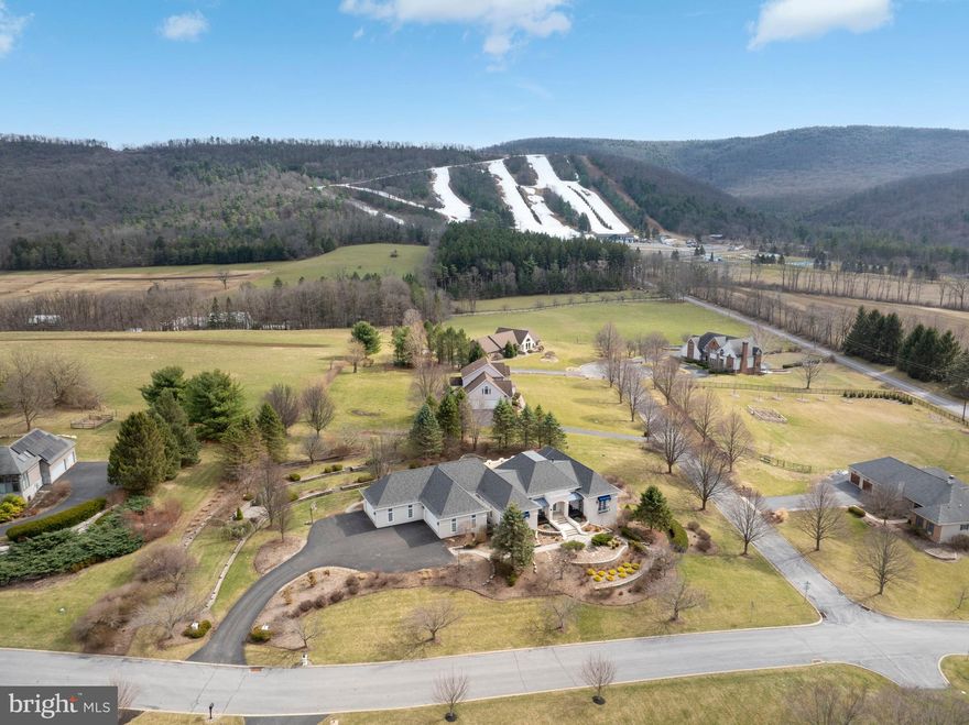 Experience refined mountainside living in the Laurel Hills community of Boalsburg. Custom built to the highest standards by Phil Bosak, this extraordinary four bedroom, four full bath, two half bath residence sits on a 1.23-acre corner lot, offering breathtaking views of Tussey Mountain’s ski slopes and Beaver Stadium, a truly rare and unforgettable setting.
Designed to celebrate the scenery, this home is all about the view. Soaring ceilings, graceful archways, ornate wrought-iron accents, and walls of windows fill the interior with natural light while framing the surrounding landscape. The stunning great room features transom-topped doors, a gas fireplace with elegant surround, and designer lighting that sets the tone for warmth and sophistication.
The gourmet eat-in kitchen is a showpiece, boasting inset cabinetry, an island with built-in double drawer beverage refrigerator, granite countertops, a Thermador gas range featuring a wok burner with hood, double ovens, professional-grade appliances, double-door refrigerator, two walk-in pantry, and a charming casement window overlooking the grounds. Adjacent main-level laundry and mudroom with Bosch washer and dryer provide exceptional functionality.
Step outside to the private courtyard oasis, complete with a sauna, hot tub, TV, and patio spaces, perfect for year-round relaxation and entertaining amid professionally landscaped hardscapes.
The primary suite is a retreat unto itself, featuring hardwood floors, crown molding, a marble-surround gas fireplace, ceiling fan, balcony access, multiple entry points, and three custom walk-in closets one with a center island. The spa-like primary bath offers dual vanities, a large walk-in shower with double heads, towel warmer, water closet with bidet, and direct access to the courtyard. Whether enjoying your veranda or the courtyard, the Tussey Mountain views remain ever-present.
A mirrored second primary suite offers equal luxury with hardwood floors, custom built-ins, walk-in closet, and an upscale bath with marble floors, whirlpool tub, stall shower, and beautiful cabinetry. 
The daylight lower level is equally impressive, accessed by wood stairs leading to a modern recreation room with hardwood floors and a marble-surround gas fireplace, seamlessly connecting to a billiards room. Two additional spacious bedroom suites, each with refined millwork, crown molding, ceiling fans, triple windows, and pocket doors, offer private en suites with marble floors, quartz vanities, heat lamps, and tub shower. Additional highlights include a powder room, second laundry with marble floors and built-ins, bonus room with hardwood floors, exercise room, extensive storage spaces with shelving, and thoughtful details throughout.
Located minutes from Mountain View Country Club, Tussey Mountain Ski Area, Rothrock State Forest, and the charming Village of Boalsburg, home to beloved shops, restaurants, parks, and breweries, this residence also offers easy access to downtown State College and Penn State. With highways nearby and nature all around, this home embodies the very best of Happy Valley living. Welcome home to Laurel Hills, where luxury, comfort, craftsmanship, and creativity converge.
