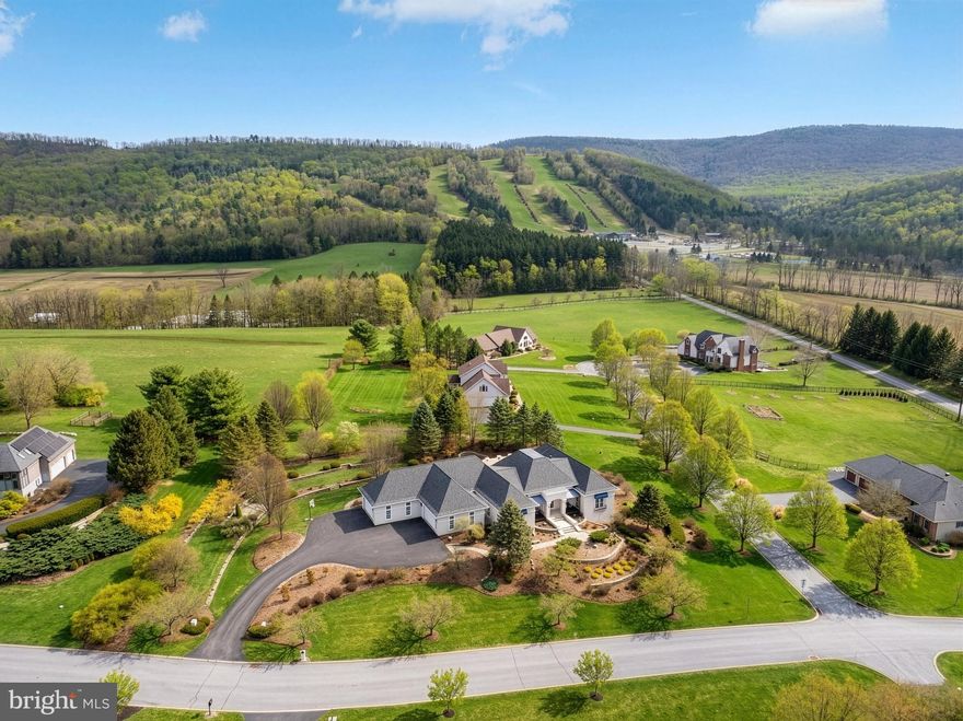 Experience refined mountainside living in the Laurel Hills community of Boalsburg. Custom built to the highest standards by Phil Bosak, this extraordinary four bedroom, four full bath, two half bath residence sits on a 1.23-acre corner lot, offering breathtaking views of Tussey Mountain’s ski slopes and Beaver Stadium, a truly rare and unforgettable setting.
Designed to celebrate the scenery, this home is all about the view. Soaring ceilings, graceful archways, ornate wrought-iron accents, and walls of windows fill the interior with natural light while framing the surrounding landscape. The stunning great room features transom-topped doors, a gas fireplace with elegant surround, and designer lighting that sets the tone for warmth and sophistication.
The gourmet eat-in kitchen is a showpiece, boasting inset cabinetry, an island with built-in double drawer beverage refrigerator, granite countertops, a Thermador gas range featuring a wok burner with hood, double ovens, professional-grade appliances, double-door refrigerator, two walk-in pantry, and a charming casement window overlooking the grounds. Adjacent main-level laundry and mudroom with Bosch washer and dryer provide exceptional functionality.
Step outside to the private courtyard oasis, complete with a sauna, hot tub, TV, and patio spaces, perfect for year-round relaxation and entertaining amid professionally landscaped hardscapes.
The primary suite is a retreat unto itself, featuring hardwood floors, crown molding, a marble-surround gas fireplace, ceiling fan, balcony access, multiple entry points, and three custom walk-in closets one with a center island. The spa-like primary bath offers dual vanities, a large walk-in shower with double heads, towel warmer, water closet with bidet, and direct access to the courtyard. Whether enjoying your veranda or the courtyard, the Tussey Mountain views remain ever-present.
A mirrored second primary suite offers equal luxury with hardwood floors, custom built-ins, walk-in closet, and an upscale bath with marble floors, whirlpool tub, stall shower, and beautiful cabinetry. 
The daylight lower level is equally impressive, accessed by wood stairs leading to a modern recreation room with hardwood floors and a marble-surround gas fireplace, seamlessly connecting to a billiards room. Two additional spacious bedroom suites, each with refined millwork, crown molding, ceiling fans, triple windows, and pocket doors, offer private en suites with marble floors, quartz vanities, heat lamps, and tub shower. Additional highlights include a powder room, second laundry with marble floors and built-ins, bonus room with hardwood floors, exercise room, extensive storage spaces with shelving, and thoughtful details throughout.
Located minutes from Mountain View Country Club, Tussey Mountain Ski Area, Rothrock State Forest, and the charming Village of Boalsburg, home to beloved shops, restaurants, parks, and breweries, this residence also offers easy access to downtown State College and Penn State. With highways nearby and nature all around, this home embodies the very best of Happy Valley living. Welcome home to Laurel Hills, where luxury, comfort, craftsmanship, and creativity converge.