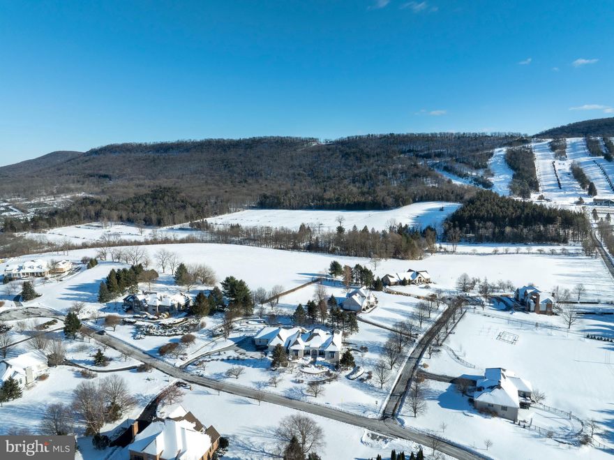 Experience refined mountainside living in the Laurel Hills community of Boalsburg. Custom built to the highest standards by Phil Bosak, this extraordinary four bedroom, four full bath, two half bath residence sits on a 1.23-acre corner lot, offering breathtaking views of Tussey Mountain’s ski slopes and Beaver Stadium, a truly rare and unforgettable setting.
Designed to celebrate the scenery, this home is all about the view. Soaring ceilings, graceful archways, ornate wrought-iron accents, and walls of windows fill the interior with natural light while framing the surrounding landscape. The stunning great room features transom-topped doors, a gas fireplace with elegant surround, and designer lighting that sets the tone for warmth and sophistication.
The gourmet eat-in kitchen is a showpiece, boasting inset cabinetry, an island with built-in double drawer beverage refrigerator, granite countertops, a Thermador gas range featuring a wok burner with hood, double ovens, professional-grade appliances, double-door refrigerator, two walk-in pantry, and a charming casement window overlooking the grounds. Adjacent main-level laundry and mudroom with Bosch washer and dryer provide exceptional functionality.
Step outside to the private courtyard oasis, complete with a sauna, hot tub, TV, and patio spaces, perfect for year-round relaxation and entertaining amid professionally landscaped hardscapes.
The primary suite is a retreat unto itself, featuring hardwood floors, crown molding, a marble-surround gas fireplace, ceiling fan, balcony access, multiple entry points, and three custom walk-in closets one with a center island. The spa-like primary bath offers dual vanities, a large walk-in shower with double heads, towel warmer, water closet with bidet, and direct access to the courtyard. Whether enjoying your veranda or the courtyard, the Tussey Mountain views remain ever-present.
A mirrored second primary suite offers equal luxury with hardwood floors, custom built-ins, walk-in closet, and an upscale bath with marble floors, whirlpool tub, stall shower, and beautiful cabinetry. 
The daylight lower level is equally impressive, accessed by wood stairs leading to a modern recreation room with hardwood floors and a marble-surround gas fireplace, seamlessly connecting to a billiards room. Two additional spacious bedroom suites, each with refined millwork, crown molding, ceiling fans, triple windows, and pocket doors, offer private en suites with marble floors, quartz vanities, heat lamps, and tub shower. Additional highlights include a powder room, second laundry with marble floors and built-ins, bonus room with hardwood floors, exercise room, extensive storage spaces with shelving, and thoughtful details throughout.
Located minutes from Mountain View Country Club, Tussey Mountain Ski Area, Rothrock State Forest, and the charming Village of Boalsburg, home to beloved shops, restaurants, parks, and breweries, this residence also offers easy access to downtown State College and Penn State. With highways nearby and nature all around, this home embodies the very best of Happy Valley living. Welcome home to Laurel Hills, where luxury, comfort, craftsmanship, and creativity converge.