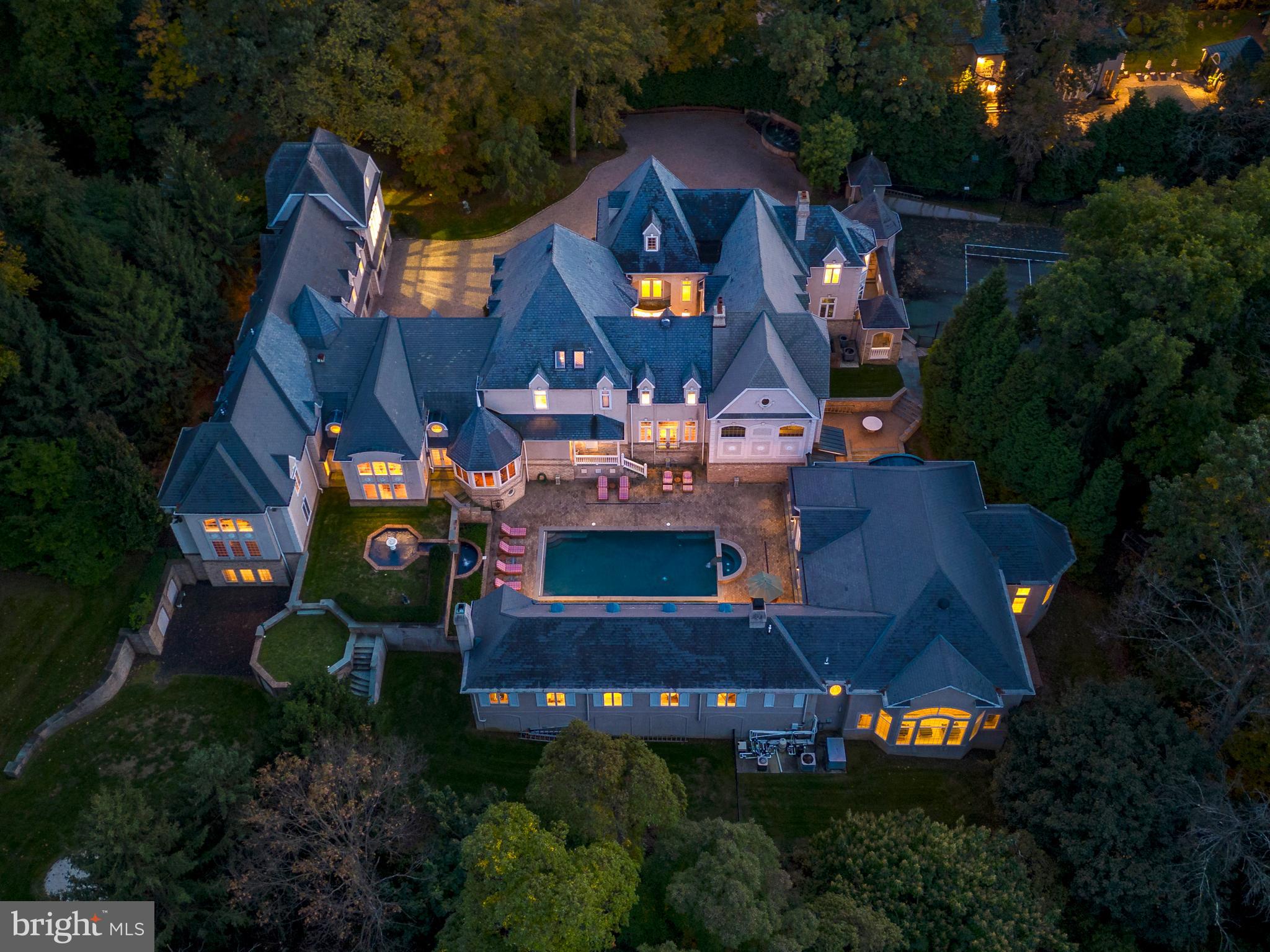 Presenting "Skyview," an expansive French Manor gracing 6.7+ acres at the end of a coveted private lane set in Villanova. A gated entrance leading to a paver courtyard with ornamental fountain sets the stage for the exceptional detail and scale of the 17,000+ sqft estate. For the sports enthusiast, the residence offers a multi-hole golf course, an indoor basketball court and a lighted outdoor tennis court. Wellness and relaxation take center stage with an outdoor pool and veranda complete with gourmet kitchen and fireplace, or step inside to a second luxurious indoor pool with separate sauna offering endless opportunities for year round fitness, recreation and entertainment. The grandeur of the residence unfolds as you traverse through the thoughtfully designed living spaces, perfect for both intimate gatherings and lavish affairs.
Enter a two story Reception Hall that exudes grandeur, with crystal chandelier, ornate ceilings, marble flooring, and a sweeping elegant staircase.The dining room and living room are designed for entertaining guests on any scale. The centerpiece of the living room is the custom limestone fireplace alongside the exquisite architectural finishes, custom flooring, opening into a full bespoke seated bar with club-quality sophistication.
The gourmet kitchen, designed by Joanne Hudson, is perfect for culinary connoisseurs, offering magnificent custom cabinetry, and professional-grade appliances, with multiple counter spaces and large seated island which is open to the sun-drenched breakfast and family rooms.
The great room features soaring ceilings, floor-to-ceiling windows that bathe the space in natural light, bespoke built-ins, a gas fireplace with custom mantel, and archways leading to the billiard/game room which is graced by coffered ceilings and a gas-burning fireplace.
A glass-enclosed wine room presents a captivating and sophisticated showcase for your curated or burgeoning wine collection, with herringbone rustic brick and wood flooring, an inviting tasting bar, and luminous storage.
Ascend the main staircase to find the expansive and tranquil Primary Suite with vaulted ceiling, Sitting Room, Dressing Room, two custom outfitted walk-in closets and a primary bathroom with soaking tub. There are an additional 7 spacious bedrooms, 9 full baths, and 3 powder rooms including a two story bedroom suite with study, and a nanny suite. The home theater is an ideal venue for movie nights and private screenings, enjoyed from the comfort of your own home.
This exquisite estate is not merely a home but a lifestyle, a retreat where every day feels like a vacation. Overflowing with an abundance of features, amenities, and unparalleled combination of grandeur, “Skyview” is a truly one of a kind estate for all seasons situated in a sought after Villanova neighborhood. Close to fine dining and shopping, convenient to the train and airports, prestigious country clubs, award winning public and private schools.