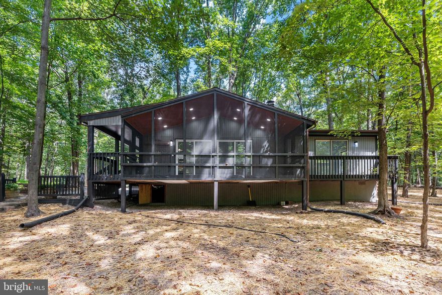 Cozy Cabin in The Woods Resort
Tucked away on a private wooded lot in the desirable Woods Resort, this charming 3-bedroom cabin blends rustic comfort with modern updates. The spacious primary suite features its own private deck, perfect for morning coffee or stargazing at night.

Enjoy the warmth of the fireplace in the newly updated kitchen and living area, complete with luxury vinyl plank flooring, granite countertops, stainless steel appliances, and upgraded lighting. Bedrooms feature brand new carpet, and the bath boasts stylish tile upgrades and a modern vanity. New Heat Pump

Relax and unwind in the large screened-in porch with beautiful lighting, or take in the peaceful surroundings from the huge front porch. A generous driveway and an outbuilding offer plenty of storage for all your gear.

Experience country living at its best—quiet, comfortable, and close to all the amenities of The Woods Resort