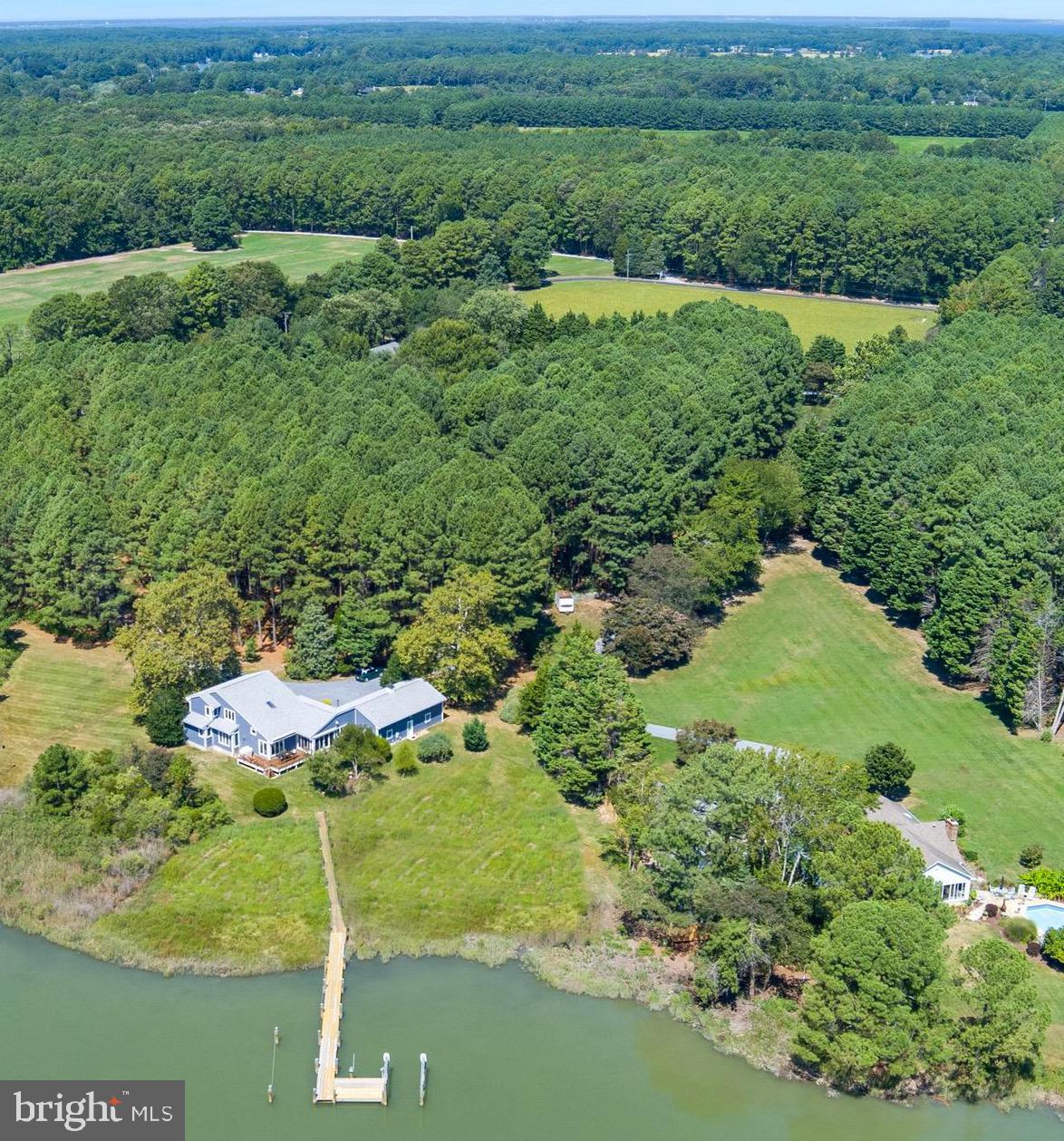 Welcome to this enchanting waterfront retreat, beautifully sited on 6.2 acres overlooking Old House Cove with scenic passage out to San Domingo Creek. Designed in a coastal style and offering 3,340 sq. ft., this 4-bedroom, 2.5-bath residence blends timeless comfort with the natural beauty of the Eastern Shore. A charming front porch sets the tone, leading into sunlit living spaces with soaring vaulted ceilings and gleaming American Cherry hardwood floors. The main-level primary suite is a serene haven with a private sitting area and spa-like bath. Upstairs, a loft lounge overlooks the living room and connects to three additional bedrooms and a shared hall bath. The gourmet kitchen, outfitted with premium appliances, flows seamlessly into the dining area, living room with cozy gas fireplace, and waterside sunroom that opens to a deck with sweeping views. A private office, versatile bonus room, and attached 2-car garage add convenience and flexibility. Outdoors, the private pier( with electricity and water) offers two slips and electric lift, inviting endless days on the water, while mature trees, lush landscaping, and native flora frame this idyllic setting. Countless updates further enhance this exceptional St. Michaels offering and a recent survey shows room for pool.