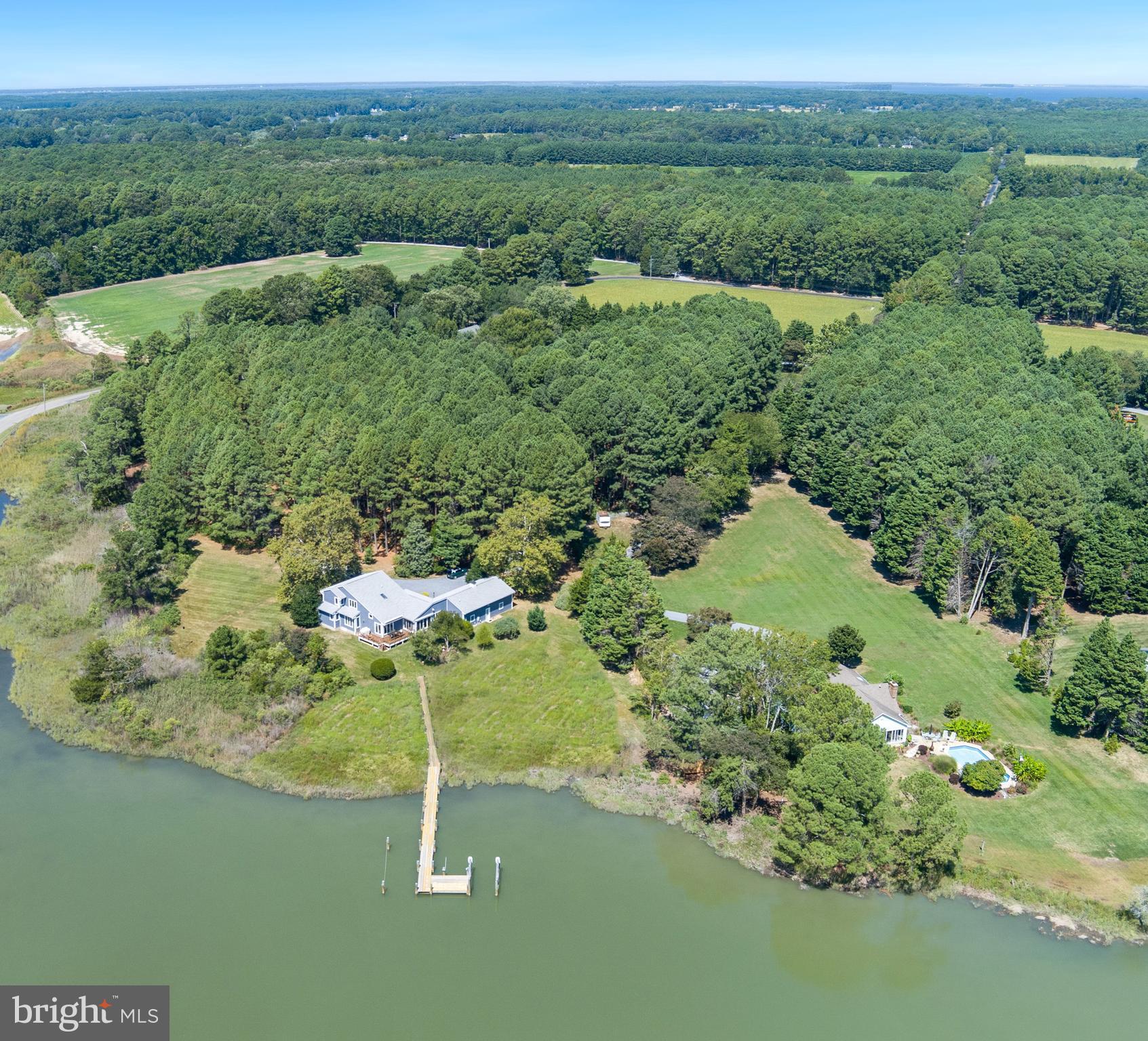 Welcome to this enchanting waterfront retreat, beautifully sited on 6.2 acres overlooking Old House Cove with scenic passage out to San Domingo Creek. Designed in a coastal style and offering 3,340 sq. ft., this 4-bedroom, 2.5-bath residence blends timeless comfort with the natural beauty of the Eastern Shore. A charming front porch sets the tone, leading into sunlit living spaces with soaring vaulted ceilings and gleaming American Cherry hardwood floors. The main-level primary suite is a serene haven with a private sitting area and spa-like bath. Upstairs, a loft lounge overlooks the living room and connects to three additional bedrooms and a shared hall bath. The gourmet kitchen, outfitted with premium appliances, flows seamlessly into the dining area, living room with cozy gas fireplace, and waterside sunroom that opens to a deck with sweeping views. A private office, versatile bonus room, and attached 2-car garage add convenience and flexibility. Outdoors, the private pier( with electricity and water) offers two slips and electric lift, inviting endless days on the water, while mature trees, lush landscaping, and native flora frame this idyllic setting. Countless updates further enhance this exceptional St. Michaels offering and a recent survey shows room for pool.