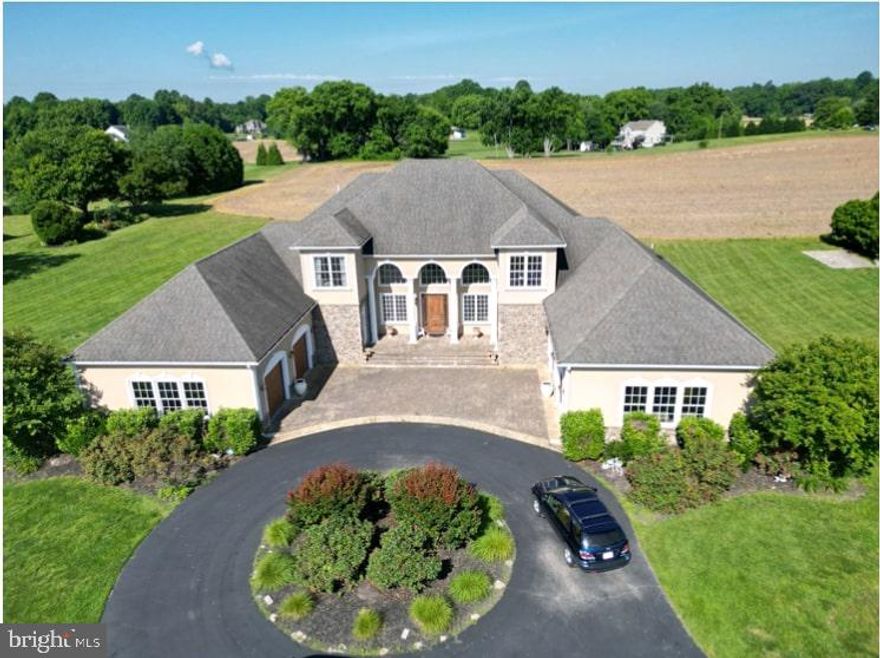 Presenting an executive custom contemporary residence prominently located on 2 acre level lot, featuring a circular driveway that gracefully leads to a U-shaped home boasting a 4-car garage evenly distributed on each side. Upon arrival, guests are greeted by a grand entrance adorned with four columns and archways. The home's exterior is characterized by stucco and stone elements, with an imposing 8-foot front door setting a tone of refined allure. Step into the foyer, where a two-story expanse commands attention, featuring arched doorways and decorative columns throughout. On the main level, discover a sumptuous owner's suite bedroom boasting 12-foot ceilings and an exquisite tray ceiling, accentuating its grandeur. This sanctuary offers direct access to the outdoor living area, seamlessly blending indoor comfort with outdoor serenity. Pamper yourself in the opulent walk-in closet, featuring a built-in dresser with a granite countertop and a meticulously designed closet organizer, maximizing both style and functionality. Accessible from both the owner's suite and the adjacent laundry room, convenience is paramount. Indulge in the en suite luxury bath, adorned with high-end cabinetry and granite countertops, framing a dual sink vanity. A resplendent tray ceiling with a decorative chandelier illuminates the space, while designer Taverne tile flooring adds a touch of sophistication. Relax in the pedestal tub or refresh in the walk-through shower, complete with multiple showerheads and a built-in bench, ensuring a spa-like experience. For added convenience, His & Her water closets provide ultimate comfort and privacy. A second main level In-Law suite bedroom awaits, featuring a Trey ceiling and a spacious walk-in closet. The en suite luxury bathroom boasts marble floors, a marble top vanity, and a step-in shower with a designer tile surround and built-in bench. The kitchen is a culinary haven, boasting commercial grade Thermador stainless steel appliances including a four-burner gas stove with griddle, complemented by a built-in pot filler faucet and wall oven with warming drawer. An oversized 11-foot island features a copper farm sink and granite countertop, accompanied by luxury amenities like pullout drawers and soft-close cabinets. The family room showcases a luxury tray ceiling and stone gas fireplace, while the living room features built-in cabinetry and an oversized sliding glass door to the outdoors. Formal dining is elevated with crown molding and a decorative chandelier. Designed for productivity, the executive office boasts high-speed internet and Wi-Fi extenders, while the upper level offers additional bedrooms (each has its own full bath), a theater/media room, and a second home office/hobby area. Outside, discover a private sanctuary featuring a covered stone patio, hot tub, outdoor half bath, and a 250,000 BTU gas fire pit, ideal for year-round relaxation and entertaining. Practical amenities include 8’ solid doors, high efficiency multi zoned heating system, LiftMaster garage door openers, and premium finishes throughout. With its architectural distinction, expansive vistas, and convenient proximity to major airports, this home epitomizes a lifestyle of sophistication and tranquility. Work in the city and live in the country. This home is only 45 mins to DCA and BWI airports. Enjoy the winding roads and picturesque farms with horses. Wake up to the sunrise on the front porch or relax and unwind to the sunsets in the back out door living area with 6 person hot tub and firepit. Don't miss the opportunity to make it yours!