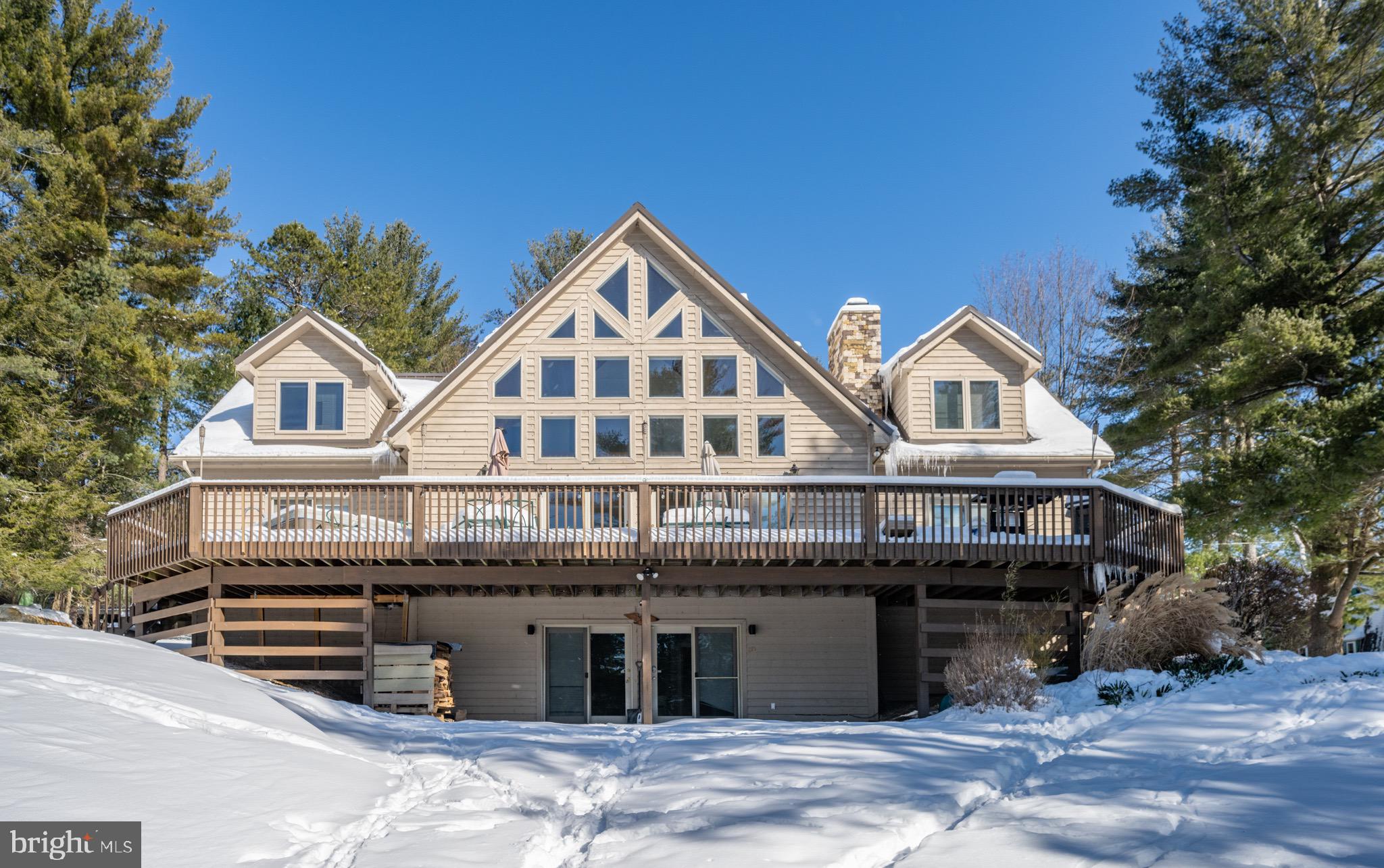 Located in a welcoming community at Deep Creek Lake, this home offers serene lake views, a private dock on split lakefront, and easy access to outdoor adventures. The bright and spacious main level features vaulted ceilings, large windows, and an open layout perfect for entertaining. The living area, with its cozy gas fireplace, flows seamlessly into the kitchen and dining spaces, which open onto a generous deck ideal for outdoor meals and relaxation. Two main-level suites provide peaceful retreats, one with private deck access and a hot tub for stargazing. Upstairs, a cozy loft adds extra space to relax, along with two additional bedrooms thoughtfully designed for comfort. The lower-level family room is a great gathering space, complete with a stone fireplace, TV, and game area. Step outside to enjoy your coffee on the expansive deck, or stroll to your private dock to swim, kayak, or fish in the lake. Ideally situated, this property is a short drive from local dining, marinas, and Wisp Resort, offering skiing, golfing, zip-lining, and more year-round activities. With nearby state parks featuring hiking, waterfalls, and sandy beaches, this Deep Creek Lake retreat is perfect for creating unforgettable memories!