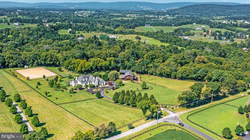 Welcome to Live Oak Farm. Nestled in the heart of Northern Virginia’s wine country, this luxurious 10 acre estate offers refined living against the backdrop of the Blue Ridge Mountains. This unique property provides the privacy and tranquility of country living, while still being convenient to shopping, dining, transportation, and world-class equestrian facilities.  

An entertainer’s dream, this 12,000+ square foot home offers plenty of space for large or intimate gatherings. The chef in your family will love the spacious kitchen featuring Wolf, Sub Zero & Miele appliances, new quartz countertops and two oversized islands. The butler’s pantry provides additional storage space and a Sub Zero wine refrigerator. Upstairs, the primary suite features a large sitting room with gas fireplace, wet bar & private deck. The primary bath features a jetted tub, oversized shower, double vanity, and a towel warming drawer.  All additional bedrooms are ensuite.  

When it’s time to play, the lower level offers expansive entertainment spaces, a gaming area, gym, bar, theater, a wine storage room, and walkout to the patio. The resort-style backyard features a deep gunite pool with dive rock, sun ledge, waterfalls, and a 40 foot waterslide.  A convenient outdoor shower and powder room will keep the wet footprints outside where they belong.  

For the equestrian in your life, this property includes a five stall barn with climate controlled tack room, laundry, and powder room.  All stalls are rubber matted and feature overhead fans and outlets.  Keep your equine babies clean in the wash stall featuring hot and cold water and overhead dryers.  Upstairs you will find a spacious 1,700+ Sq. Ft. 2 bedroom, 2 bathroom apartment featuring a full kitchen with stainless steel appliances and granite countertops.  The barn offers direct turn-out to three paddocks, each with water and electric.  A 48 foot long garage with front and rear doors provides extra parking and storage space.  Keep your hay and equipment protected in the spacious 24’ x 48’ utility barn.  The 140’ x 200’ riding arena featuring Airfoot™ footing can accommodate any discipline.  For the nature lover, there are plenty of mature specimen trees on the property that attract birds year-round.  

Enjoy the pleasure of picking fruit from your own mature fruit trees and berry bushes, including Asian pears, peaches, and apricots as well as blackberries.  Come find your happy place at Live Oak Farm!  Owner agent.