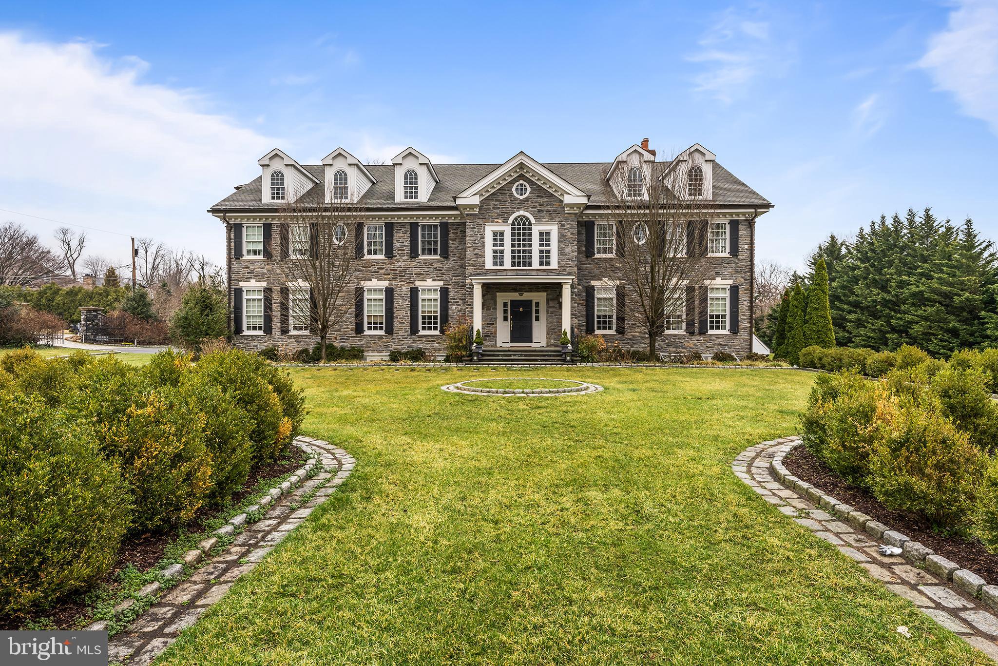 Built in 2005 this handsome 7 bedroom 7+ bath stone mansion style home, designed by Tom Hall architect, impresses with high ceilings substantial millwork, streamlined open floor plan, and richly stained hardwood floors. Finished on four levels, the exterior of this home was patterned after the landmark properties of the mainline while the interior was designed for an active modern family in mind. Enjoying western light through a gentle arch, the two story Foyer opens to the Living Room on right featuring a fireplace and well crafted millwork and the Dining Room to the left also warmed by a fireplace and connected to a well outfitted Butlers Pantry with wine chiller and overhead display cabinetry . Sunlit, the straight-through Foyer leads to views of the covered terrace and pool with notable details including the family room’s coffered ceiling, wall of windows and French door access to the rear yard and gardens. The open flow between the large kitchen and family room is what makes this traditional looking house not so traditional. Crisp white walls with hide-away cabinetry and mill work flank the TV and gas burning fireplace wall. Adjacent, a stunning modern Kitchen sparkles with white cabinets, black honed stone counters and a suite of highest end appliances including Thermador professional series range with 6 burners, griddle and two full sized ovens, Viking warming drawer and Sub-Zero freezing and refrigeration.... Two islands, one seated and the other centrally positioned for prep and washing up, combine to create a space that is as much display as welcoming and functional. Steps away the Breakfast Room, designed in solarium style and positioned for morning sun, connects to the family room, kitchen and terraces. A large informal entrance acts as the hub to an oversized mudroom with generous coat and Costco storage, entrance to the five car garage and back courtyard. Off this family space, a home office with paneled wainscoting and open shelving manages all the paperwork that comes with daily life discreetly and neatly out of view. Two powder rooms complete this level. Ascend the sweeping front stair to the second level. An airy Primary suite has it all. The bedroom itself features a gas burning fireplace, tray ceiling with stepped lighting, French doors to a deep rear facing balcony, sitting room with TV wall and additional storage and gorgeously outfitted closet and bath. The under window jetted tub, separate stone topped vanities, private water closet and large, seated steam shower begin and ends the day indulgently. Four other family or guest bedrooms each with their own bath are located down a wide hall with gleaming hardwood floors. Additionally, a large second floor family or AV room features a kitchenette and another bedroom and en-suite bath. The back stair connects all four finished levels with the third floor offering large finished open space, ideal for Au pair or storage with a bedroom and full bath. With a walk-out to a small flagstone terrace and garden, the lower level is finished with the same degree of style and attention as the other areas of the home. A spacious open recreation room with seated bar and kitchenette is adjacent to a re-purposed bank vault which houses the temperature controlled wine collection. A large gymnasium, full bath, generous storage and mechanicals complete this level. Highly style and beautifully proportioned with a proper balance between formal and informal areas. The home offers the old estate feel with the in demand interior appointments and modern, open floor plan.