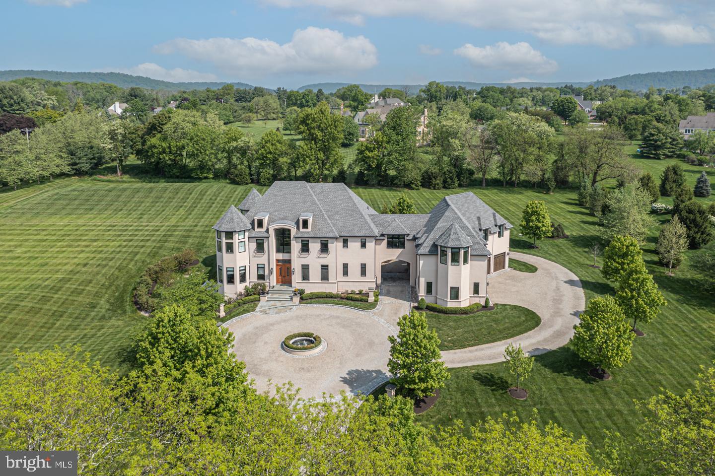 Style and luxury nestled on almost 4 acres in a small enclave of homes in Upper Makefield offering privacy and breathtaking views of the historic Bucks County countryside. Beautiful and thoughtful designer elements set this 5 bedroom Zaveta estate apart and lend to a true sense of upscale living. The entry is stunning with its French country aesthetic including a gravel courtyard and mahogany and wrought iron double doors that set the tone for the rest the home. Thoughtful amenities include 3 paneled doors, motorized shades on the grand windows, soaring ceilings and an elevator that accesses each level. The extensive living space indoors and out is the ideal setting for entertaining friends and family. Inside, an open floor concept with a gorgeous designer kitchen highlighting wood and marble accents, oversized breakfast bar, and 2 waterfall islands opens to the chic gathering room, flooded with natural light from a wall of floor to ceiling transom windows and doors, designed to accommodate both large and small gatherings. The upper level is equally impressive and includes the primary suite, which is set apart unto itself, and enjoys a lovely combined sitting and office area, walk-in closets, terrace overlooking the grounds, and an oversized spa-like bath with a freestanding soaking tub and walk-in shower with multiple shower heads. A separate wing of symmetrical bedrooms and baths nestled between the turrets can be closed off for privacy along with the additional 2 bedrooms and bath completing the upper level. The walkout lower level offers fantastic flexibility and features a gym with glass walls, 3 person sauna, full bath, and media room. A porte cochere leads to an oversized 4 car garage complete with epoxy floor and high ceilings for the true car enthusiast. Outside, a blue stone patio rests below a sprawling louvered pergola complete with heat and lighting for year-round leisure. Enjoy an outdoor kitchen with grilling station, fire pit, hot tub, and multiple lounging and dining areas all with magnificent views of the water feature embedded in the lush landscape amidst the wooded backdrop making this luxury estate a truly spectacular living and entertaining experience.