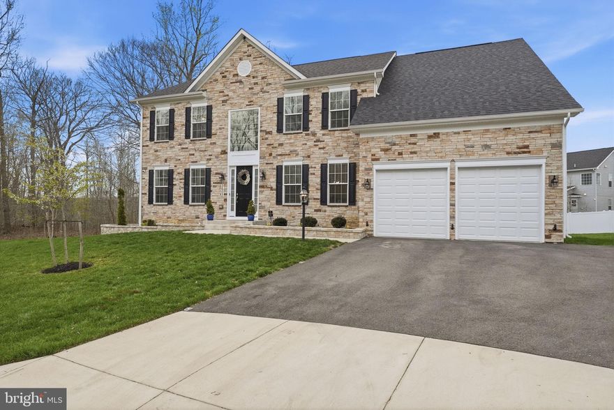 Tucked away on a quiet cul-de-sac, this stunning stone-front home makes an unforgettable first impression with exceptional curb appeal, professionally landscaped grounds, and elegant exterior lighting that creates a striking presence both day and night. A spacious two-car garage and concrete lead walk complete the refined exterior, while mature trees and thoughtful plantings frame the home in natural beauty.
Step inside to a grand two-story foyer highlighted by a dramatic waterfall staircase with modern contrasting finishes, setting the tone for the refined design and high-end craftsmanship found throughout. The thoughtfully designed main level features a private home office perfect for today's work-from-home lifestyle, along with a formal living room and dining room enhanced by crown molding and chair rail detailing — offering both versatility and timeless appeal for everyday living and elevated entertaining.
At the heart of the home, a breathtaking two-story family room is filled with natural light from an expansive window wall and anchored by a stunning gas fireplace with a custom mantel. A coffered ceiling adds architectural drama, while the space flows seamlessly into the gourmet kitchen and morning room, creating an open and inviting layout ideal for gatherings of any size. The gourmet kitchen is truly designed to impress, featuring a generous quartz island with seating, a 36-inch gas cooktop, premium stainless steel appliances, custom 42-inch cabinetry, designer pendant lighting, and a deep farmhouse sink. The open-concept design connects effortlessly to the main living areas, while a custom mudroom and alternate laundry location add everyday convenience and functionality.
Upstairs, four spacious bedrooms include a luxurious primary suite with a tray ceiling, custom walk-in closet, and a spa-inspired bath complete with dual vanities, a soaking tub, and an upgraded walk-in shower with custom tilework and built-in seating. A secondary bedroom suite with its own full bathroom provides added flexibility, ideal for guests or multigenerational living, while a buddy bathroom enhances convenience for the remaining bedrooms. Designer light fixtures, brushed nickel hardware, and plush carpeting carry the upscale finishes throughout the upper level.
The fully finished basement expands the living space with a large recreation area, dedicated exercise room, a full bathroom, and abundant storage — perfect for movie nights, hobbies, or hosting overnight guests. A double areaway with slider provides easy walk-up access and floods the lower level with natural light.
Outdoor living is equally impressive, featuring a stamped concrete patio with a built-in circular fire pit and raised stone seating wall — an ideal setting for entertaining under the stars. An expansive composite deck overlooks a private wooded backdrop with mature trees, offering both seclusion and tranquility, while professionally installed outdoor lighting enhances the ambiance well into the evening. Front and rear hose bibs and a thoughtfully designed landscape package complete the exterior.
With 9-foot ceilings on all three levels, energy-efficient systems including high-efficiency natural gas heat, Low-E windows, and a HERS-certified building envelope, plus quality craftsmanship in every detail, this home offers a rare blend of luxury, space, and functionality. All of this is set in a highly desirable location with quick access to commuter routes, premier shopping, diverse dining and everyday conveniences. A truly exceptional opportunity to own a home that lives as beautifully as it shows.