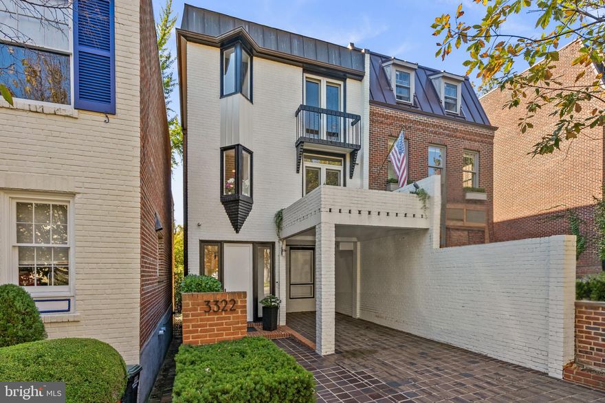 A rare mid-century contemporary in the heart of historic Georgetown, this 1968 residence brings light, volume, and architectural clarity to one of the city’s most coveted neighborhoods. Designed in the spirit of Hugh Newell Jacobsen’s clean, modernist aesthetic, the home unfolds across 3,436 square feet of open, multi-level living, defined by soaring ceilings, clerestory windows, and a dramatic wall of floor-to-ceiling glass that captures its prized southern exposure. 
Natural light pours through five skylights and expansive glazing, illuminating the home’s sculptural original staircase and fluid public spaces as the hallmarks of timeless mid-century design. The layout offers a seamless balance of openness and intimacy, ideal for both everyday living and sophisticated entertaining.
In 2024, the interiors were thoughtfully refined by Skip Sroka of Sroka Design, whose vision brought a fresh sense of calm and elegance to the space. Custom millwork, artful mural panels, celadon-hued walls, and a redesigned fireplace anchor the living room, creating an atmosphere that feels at once modern, serene, and effortlessly chic.
Outdoors, the home unfolds into a private, architecturally inspired garden that feels worlds away from the city. The deep, south-facing rear patio is bathed in sunlight throughout the day and beautifully landscaped across multiple terraced levels, creating a series of intimate spaces for dining, relaxing, and entertaining. A striking pergola anchors the garden, while mature plantings and ivy-clad brick walls provide a rare sense of privacy and tranquility. Multiple balconies extend the living experience outdoors on every level offering elevated views and fresh air at every turn. Completing the home’s exceptional livability is a carport providing TWO off-street parking spaces, a true luxury and a rare find.
Featured on the 2024 Georgetown House Tour, 3322 Dent Place NW stands as a truly distinctive offering where architectural pedigree, natural light, and refined design converge in one of Washington’s most iconic settings.