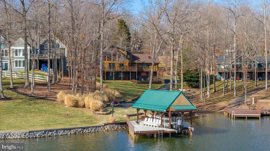 Welcome to an impeccable opportunity to own a custom log home on the public side of Lake Anna, Virginia. This one-of-a-kind residence features rare Hand-Hewn logs brought in from Montana, something rarely seen in Virginia, and expertly assembled to create this stunning custom-built retreat.

As you arrive, you are greeted by a long, beautiful private paved driveway offering plenty of space for parking, guests, and storage. From the moment you walk up to the home, you are immediately struck by the craftsmanship and presence of the grand log construction.

The home spans three finished levels.

Upon entering, you will immediately notice how bright and airy the home feels, enhanced by south-facing exposure overlooking the water, boathouse, and cabana. On the main level, you will find a stunning custom kitchen thoughtfully designed to face the lake, complete with high-end upgrades, custom fixtures, and grand A-frame windows that capture open water views. This level also includes the laundry room, a full bath, and a bedroom for convenient main-level living. Impeccably maintained, the kitchen flows seamlessly into an open-concept dining and seating area, perfect for entertaining. The large living room features expansive glass and direct access to the full wraparound deck overlooking the lake. The wraparound porch extends all the way to the lake side of the home, offering incredible space for entertaining. 

Upstairs, the loft offers even more breathtaking views through the A-frame windows. The primary suite is privately situated on this level and features a spacious bathroom and dedicated space for a home office overlooking the lake.

The lower walkout level is built for entertaining, featuring a bar and den area, an additional bedroom, and a full bathroom with a large jetted tub. The jets circulate air rather than water, eliminating buildup concerns. You will also find an immaculate mechanical room on this level. The bar area is hard-wired for speakers that extend through the bathroom and outside to the fire pit area, creating a fully integrated entertaining experience. Access the attached spacious 2 car garage from this level. 

This meticulously maintained home includes high-end fixtures and finishes throughout, including but not limited to: solid white oak hardwood floors, Dekton countertops, Vermont Castings wood-burning stove, LG washer and dryer, Bosch induction stovetop and dishwasher, LG electric and convection wall oven, two microwaves and custom lighting throughout. 

Stepping off the expansive decking and heading toward the water, you will find a paved path that connects to your private boat and jet ski launch, then winds down to the boathouse.

With approximately 150 feet +of shoreline, there is ample space to relax and enjoy lake life. Approximately 90 feet of shoreline is bulkheaded, offering enhanced erosion protection.

The expansive boathouse is positioned in approximately 9 feet of average water depth and features a spacious sun deck, along with a boat slip built with aluminum metal dock material and equipped with a lift.  A four-seasons cabana with WiFi that can be heated and cooled for year-round use. The cabana is wired for surround sound, includes a bar area, and offers incredible opportunities for waterfront entertaining. Enjoy outdoor living at its finest, whether watching TV in the boathouse with heat and AC, relaxing by the water, swimming off the dock, or heading out on the lake.

Located in the sought-after Wyndemere community, amenities include multiple boat launches, basketball courts, and more. High-speed internet is available. Short-term rentals are allowed.

Optional boat purchase and furniture package available separately. See attached MLS documents. View the 3D Tour and Video!