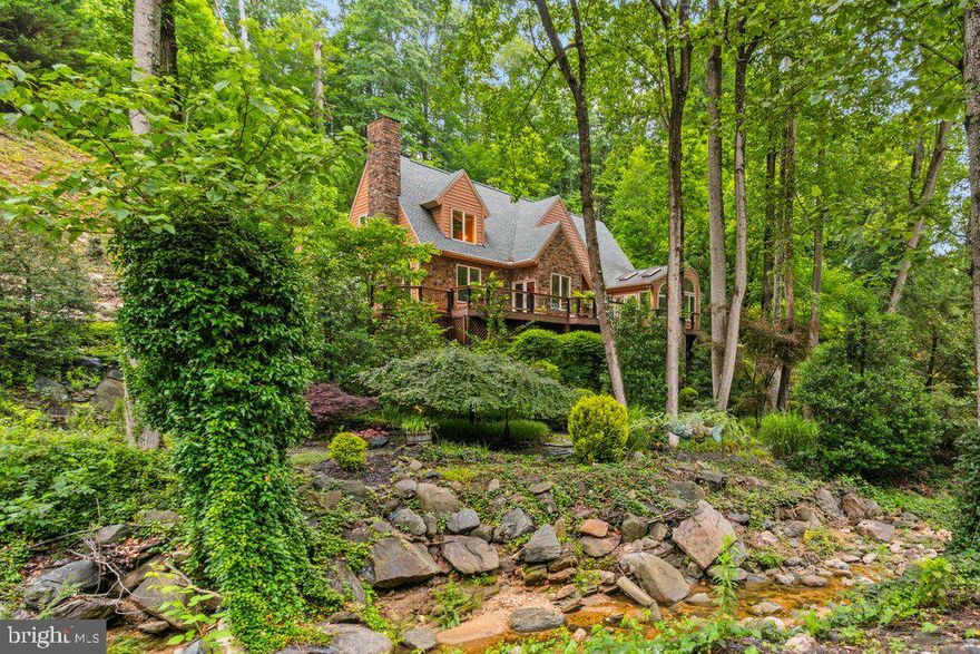 Located in Cromwell Valley - Experience exceptional design and tranquility at 2407 Cub Hill Road—an architect-designed custom home set on a picturesque 1.08-acre lot bordered by a stream and surrounded by over 13 acres of protected conservation easement land. Thoughtfully updated and immaculately maintained, this one-of-a-kind property combines timeless craftsmanship with modern comfort, offering 4 bedrooms, 2 full baths, and nearly 2,600 square feet of finished living space.

The main level features 9-foot ceilings, formal living and dining rooms, a sun-filled sitting room, and a spacious family room with a pellet stove that flows into a four-season sunroom with hot tub. The gourmet kitchen is equipped with granite counters, custom cabinetry, island seating, and high-end appliances including a JennAir wall oven, newer cooktop, 1-year-old refrigerator and microwave, and a recently updated washer and dryer. Travertine tile and hardwood flooring extend throughout the main living spaces. A full bath on the main level was completely renovated six years ago.

Upstairs, vaulted ceilings and generous natural light create a peaceful retreat. Custom cabinetry in the upstairs bathroom, ample closet space, and Andersen windows throughout (including 4 recently replaced units and an upgraded skylight with 2 spares on hand) further elevate the home’s enduring quality. The entire interior was professionally painted in 2022.

Step outside to enjoy the wrap-around TimberTech deck, real cedar siding refinished in 2021, a 2022 architectural roof, and commercial-grade gutters and guards installed in 2021. The night-lit property includes a gated driveway with remote entry, lush landscaping, a pond, and a stream that is maintained by Baltimore County that runs the length of the lot.

For the hobbyist or car enthusiast, there are two detached 2-car garages—both wired for stereo systems, interior and exterior lighting, and protected by an ADT security system. The upper garage features a full garage door, half bath, and dedicated electric service. The main home is also protected by ADT with motion sensors, and features a propane-fueled generator for whole-house backup power. The well system is supported by a 2023 Atlantic Blue water softener and saltwater filtration system. Two water heaters (one just 2 years old) provide ample hot water throughout the home.

Additional amenities include recessed lighting, built-in sound system, a kitchen TV (included), and Verizon Fios connectivity. The basement, while unfinished, includes a workshop area, utilities, screens, and ample storage potential.

Truly a rare opportunity to own a thoughtfully designed, meticulously upgraded property offering unmatched privacy, functionality, and charm.