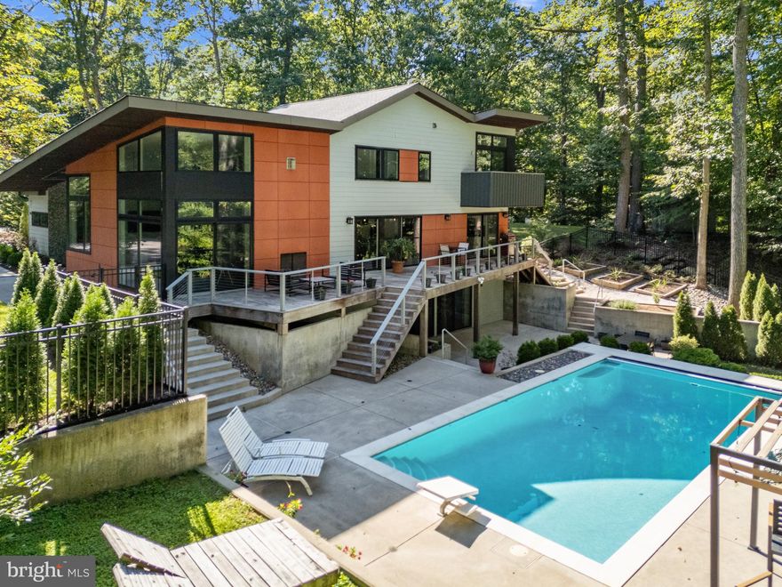 Extraordinary residence located in the prestigious Downs on the Severn community of Annapolis. This 5 bedroom, 5.5 bath home with over 4,300 sqft of living space was completely renovated and expanded from the ground up in 2016 and seamlessly combines luxury with eco-conscious living. Designed by renowned DC architect Catarina Ferreira and constructed by Del Sesto Construction, the home exemplifies sustainable elegance with meticulous attention to detail. This residence incorporates spray foam insulation, high-performance Andersen windows, geothermal heating by WEHN HVAC and two Tesla-ready EV chargers providing a responsible, energy-efficient living environment without sacrificing design. Step into the stunning 2 story Living room with walls of windows, open tread staircase with glass railing and awe-inspiring fireplace which is the focal point of the room. At the heart of this home lies a chef's dream kitchen, complete with Italian-imported Zampieri cabinets, a Jenn-Air induction cooktop, enormous center island and KitchenAid double wall ovens. Curated finishes including designer lighting and a leather-pressed granite bar create an atmosphere of sophisticated comfort, ideal for entertaining or enjoying intimate gourmet meals. Spanning multiple levels, the home offers a variety of flexible living spaces. The main floor is designed for entertaining, yet also includes an office that doubles as a guest suite with whimsical loft space, metal library ladder and secret door. Upstairs, you’ll find three bedrooms, each with hardwood floors, ensuite bathrooms and custom closet organizers. The primary suite stands out with modern fireplace, soaring ceiling, walk-in closet, and a spa-inspired bathroom with natural light from skylights and solar tubes. Completing the upper level is a conveniently located laundry room. The fully finished basement with guest suite, gym, full bath and direct access to the patio and pool provides additional flexibility for accommodating guests or extended family. Step outside to experience unparalleled outdoor living with Ipe decking and cable railing on upper deck, complemented by the stunning heated saltwater pool with an automatic retractable cover. Surrounded by trees for the ultimate private setting, the sparkling pool is the ideal place to relax and enjoy the serene environment. This residence not only offers a private retreat but also access to a plethora of community amenities, including tennis courts, pickleball courts, two marinas including the new floating dock marina, and access to the Severn River and Chesapeake Bay. Whether you desire a secluded lifestyle or easy access to Annapolis, Washington D.C. and Baltimore, this home provides the perfect balance of tranquility and connectivity. Welcome Home!