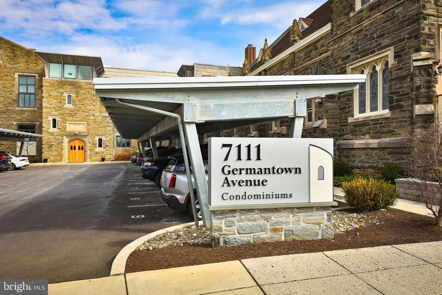 In 2020, Mount Airy Presbyterian Church was acquired by two local developers who built 19 condominiums, no two the same, keeping many of the original architectural features. Unit 206 is part of "the church hall".  This is a well-maintained complex that offers a community garden and outdoor living space, 
The location truly can't be beaten! You'll love being just a short walk away from public transportation, the library, and all the charming shops, cafes, and restaurants that downtown Mount Airy offers.
The open-plan first floor features a gourmet kitchen with high-end Samsung appliances: an induction range with a convection oven, side-by-side fridge over drawer freezer, D/W, and microwave. Quartz counters top an island, with solid cherry cabinets throughout. The living area runs 27 feet, with sliders opening to a balcony and deep-silled windows providing abundant light on the quiet northeastern side. Also on the main floor are a full-sized stacked washer and dryer, concealed by louvered doors. A full bath is at the north end. Up four steps is a guest bedroom, which the owners have equipped with a convertible sofa. Closet space abounds upstairs and down, with a linen closet at the top of the main staircase. The original exposed brick and trusses are among the historical details that characterize the second upstairs bedroom. Light pours through triple casement windows in the hallway and the main bedroom. The generously sized main bedroom features an en suite bathroom with a glass shower enclosure and a large custom closet. Unit 206 has a 2-car covered parking bay with access to 230-volt EV chargers. This condominium association has a strong reserve and sound management.  There are six years left on the tax abatement.